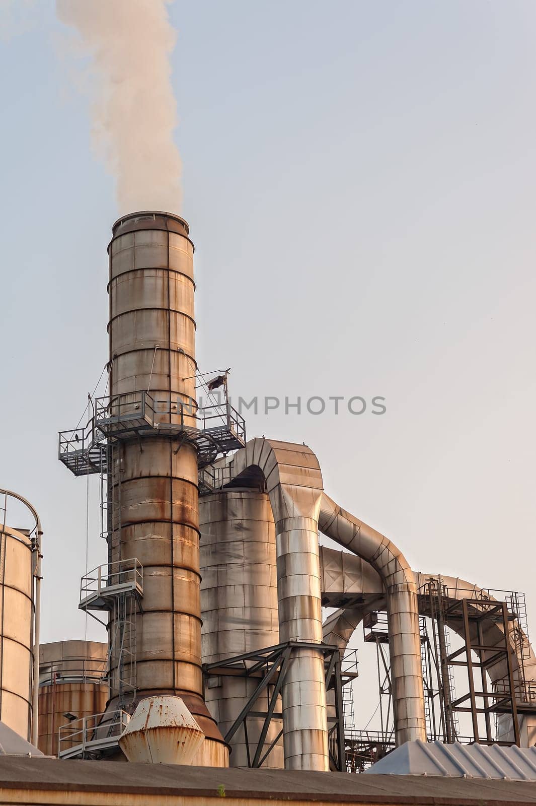 Chemical plant at sunset. Silos and smokestacks of a factory.