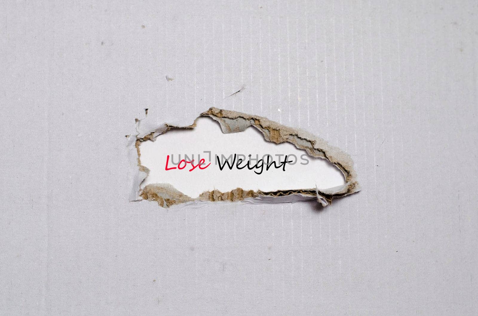 The word lose weight appearing behind torn paper