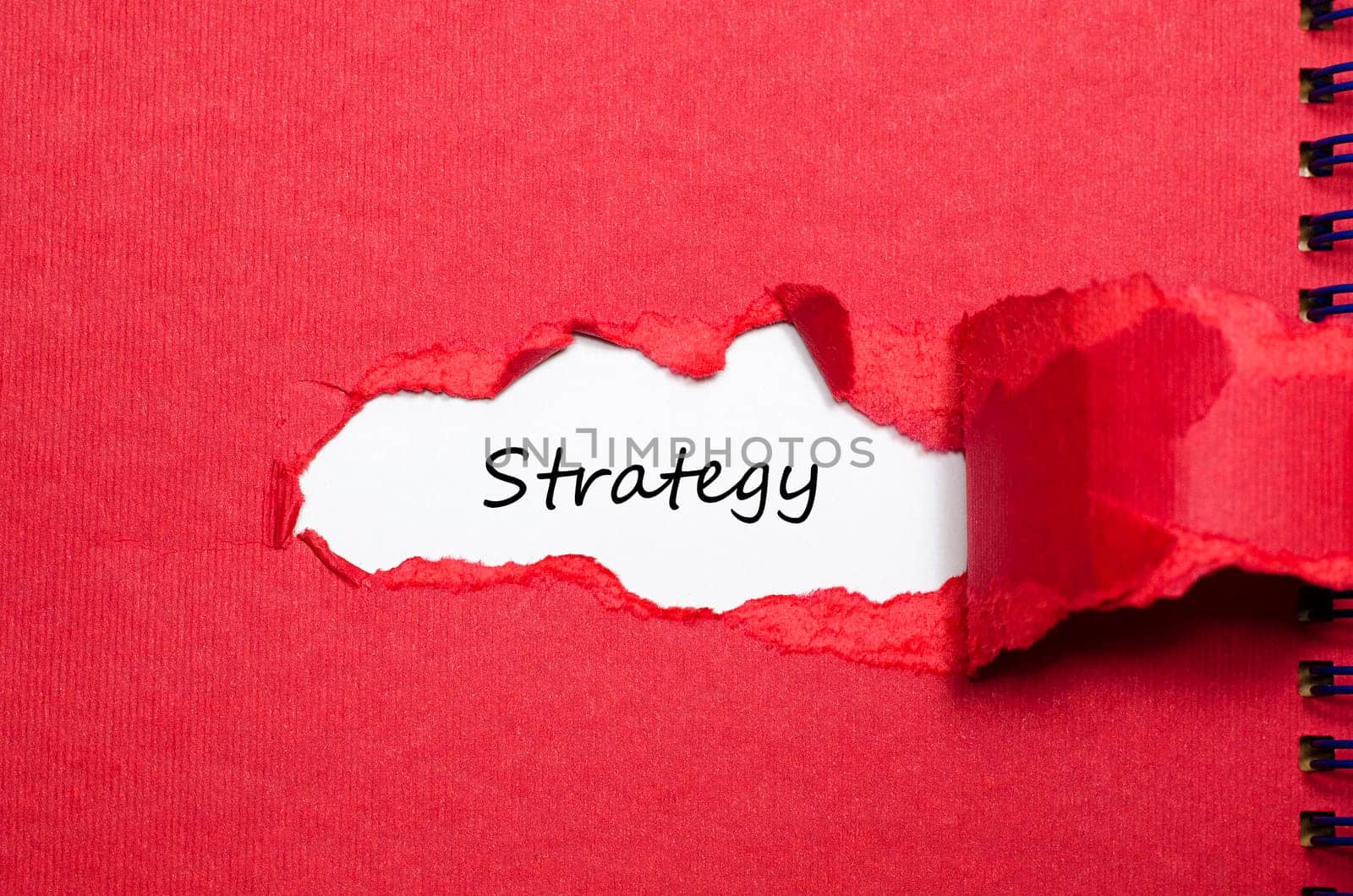 The word strategy appearing behind torn paper