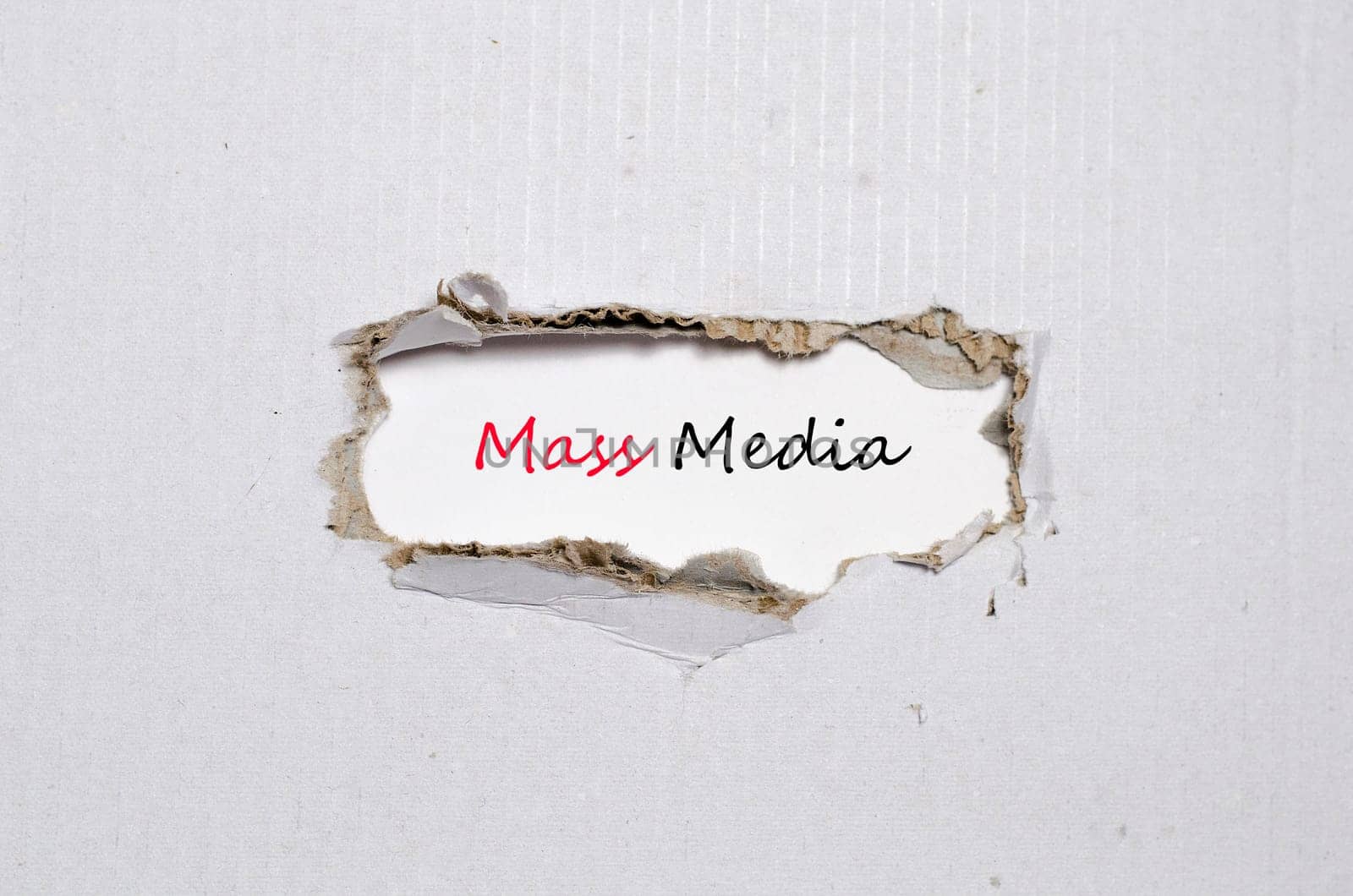 The word mass media appearing behind torn paper