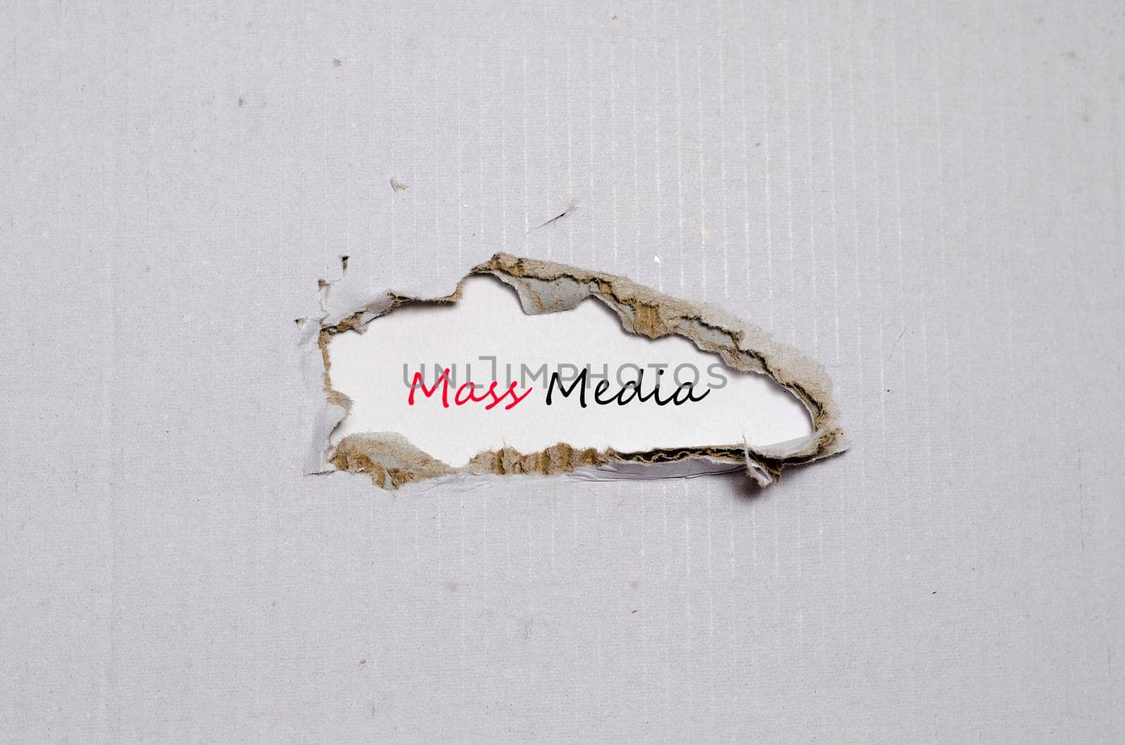 The word mass media appearing behind torn paper