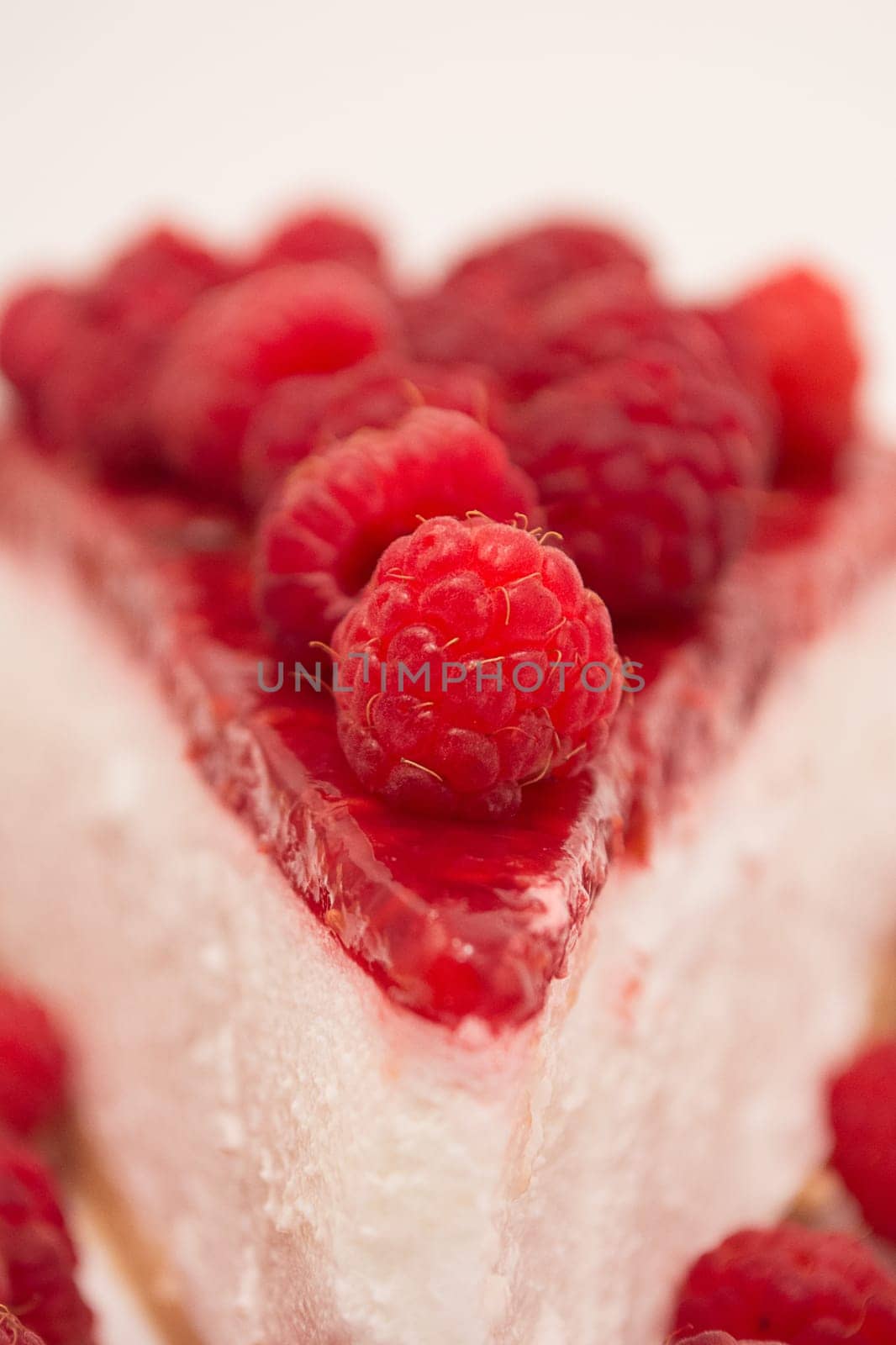 Cheesecake slice with raspberries on a white plate isolated on a white background