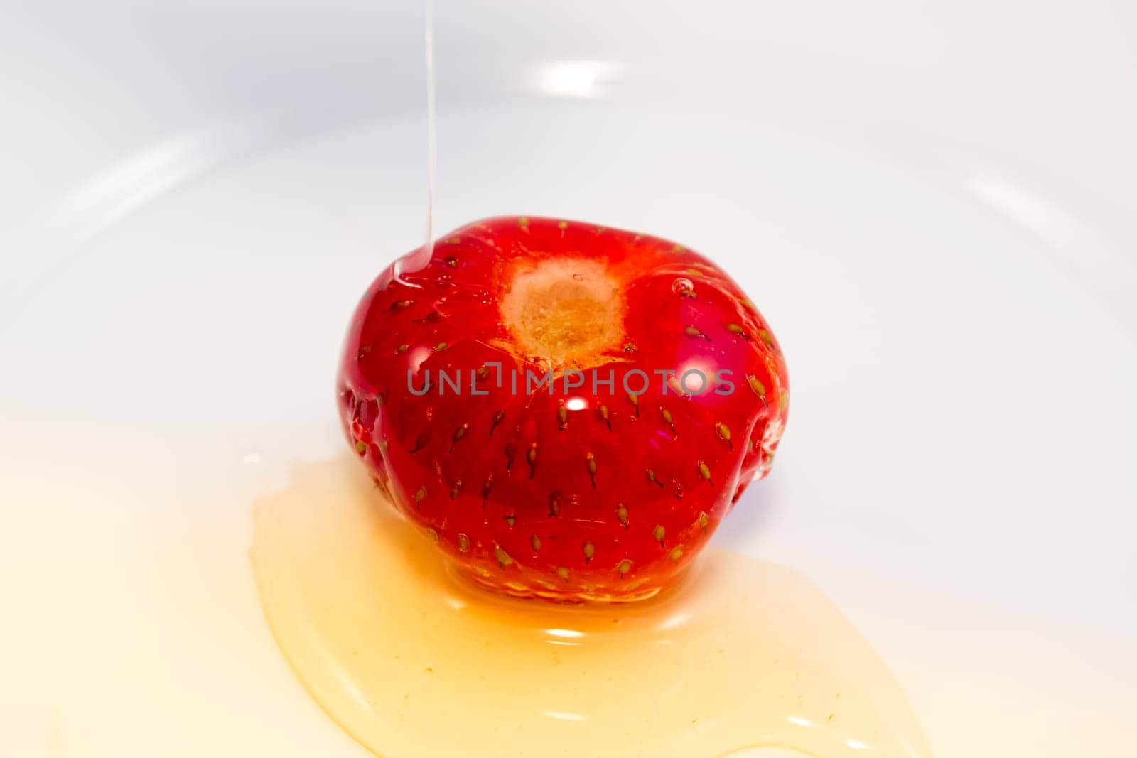 Honey pouring over small strawberry