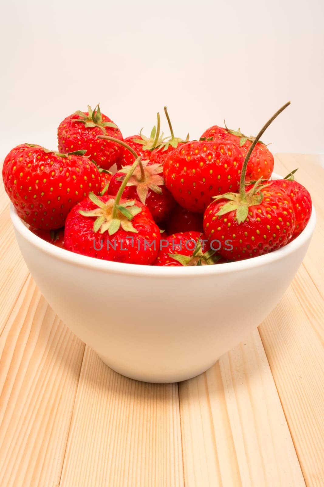 Strawberry in the bowl on the wodden table and white background