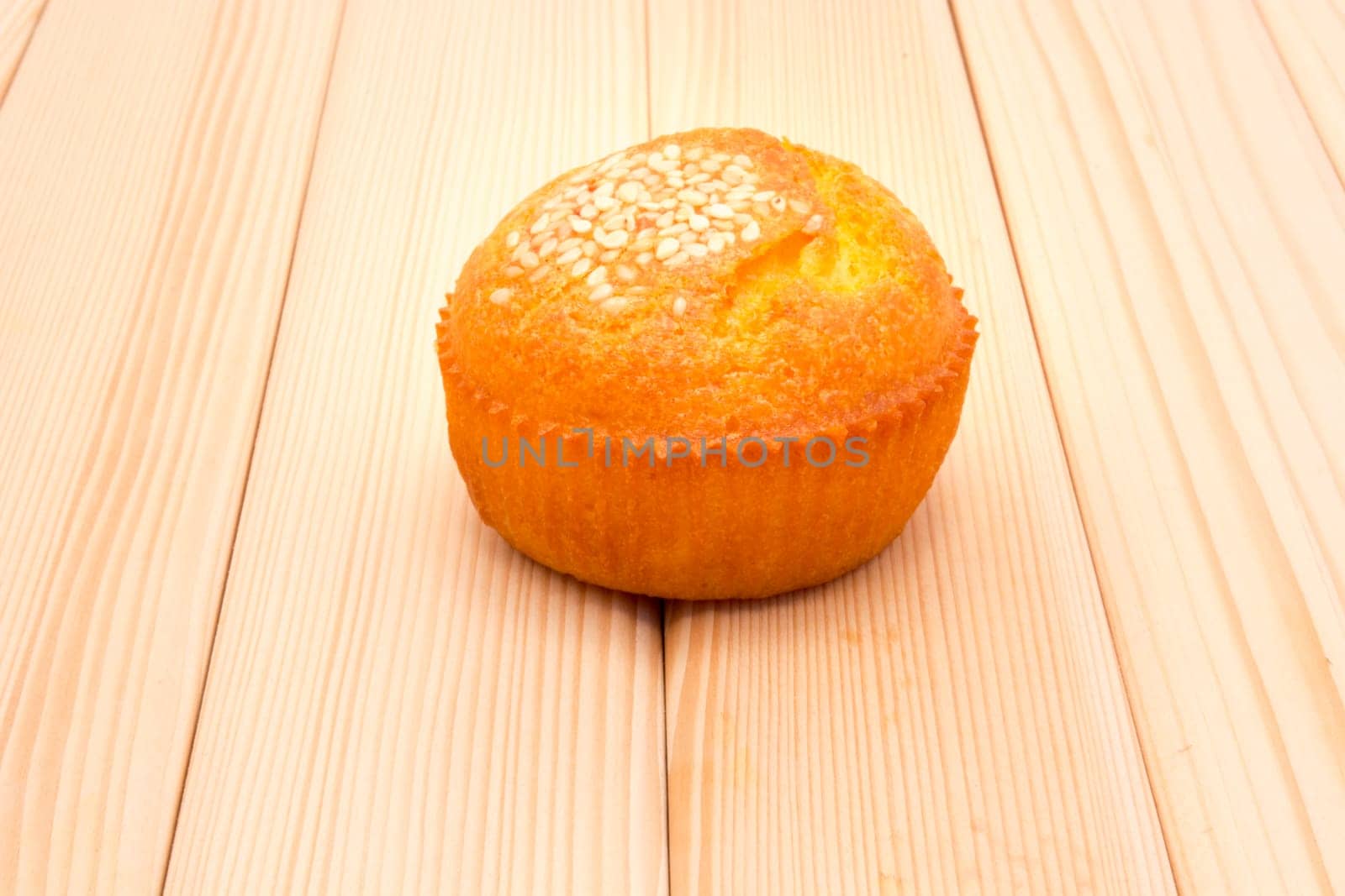 Muffin with sesame seeds on top lying on table