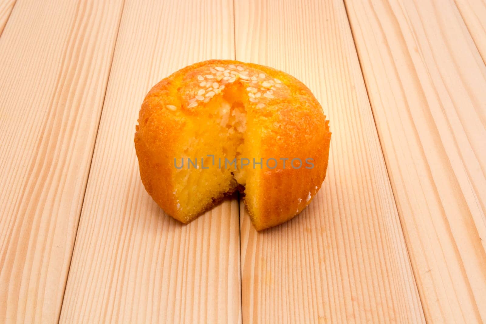 Muffin with sesame seeds on top lying on table