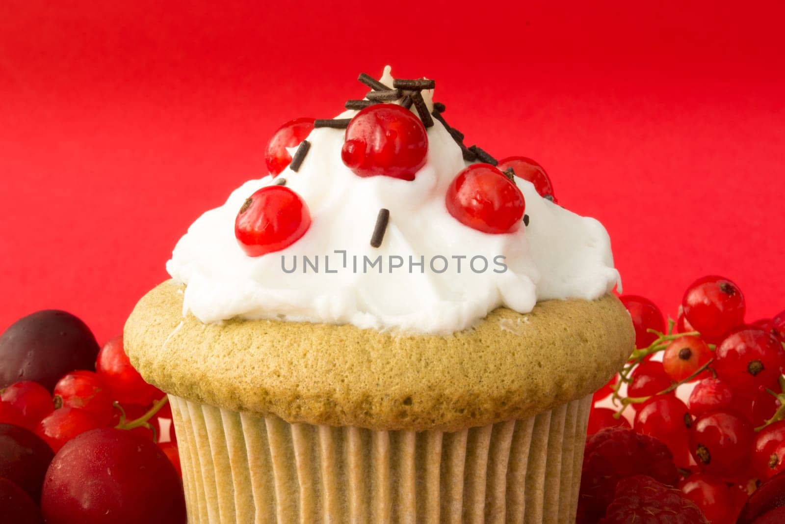 Sweet cupcake with red berries, cherrries and chocolate crumbs on a plate