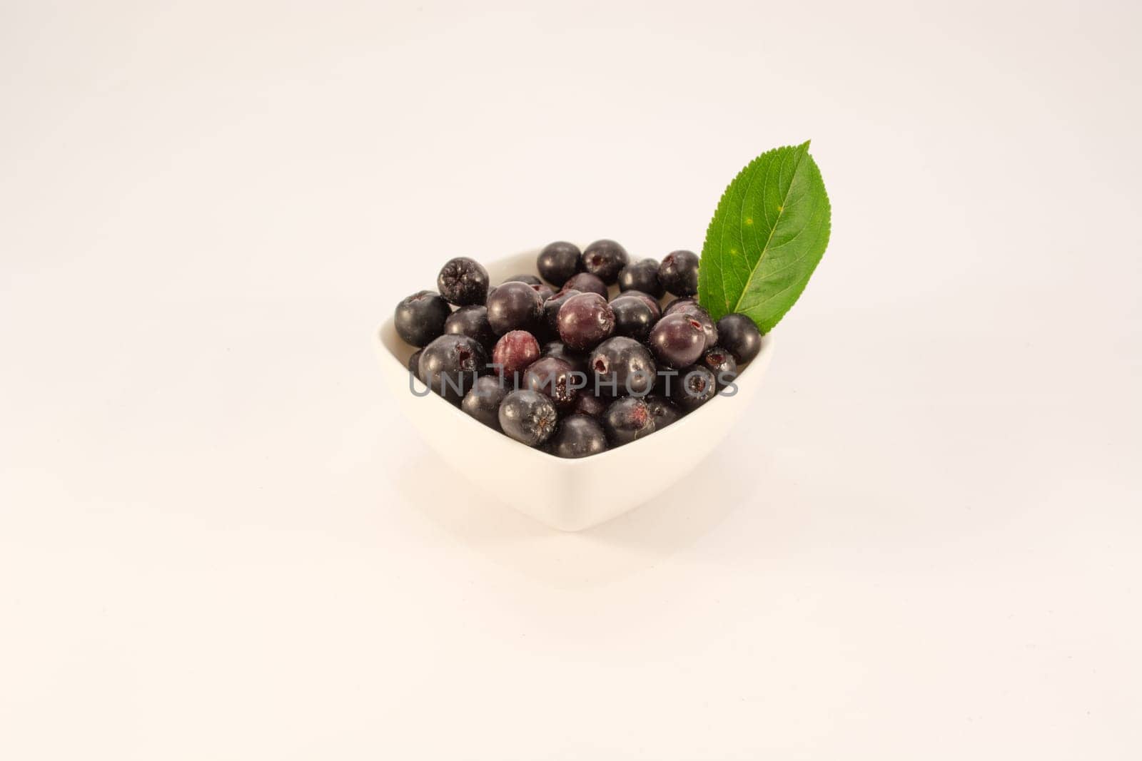 White bowl full with fresh and tasty aronia