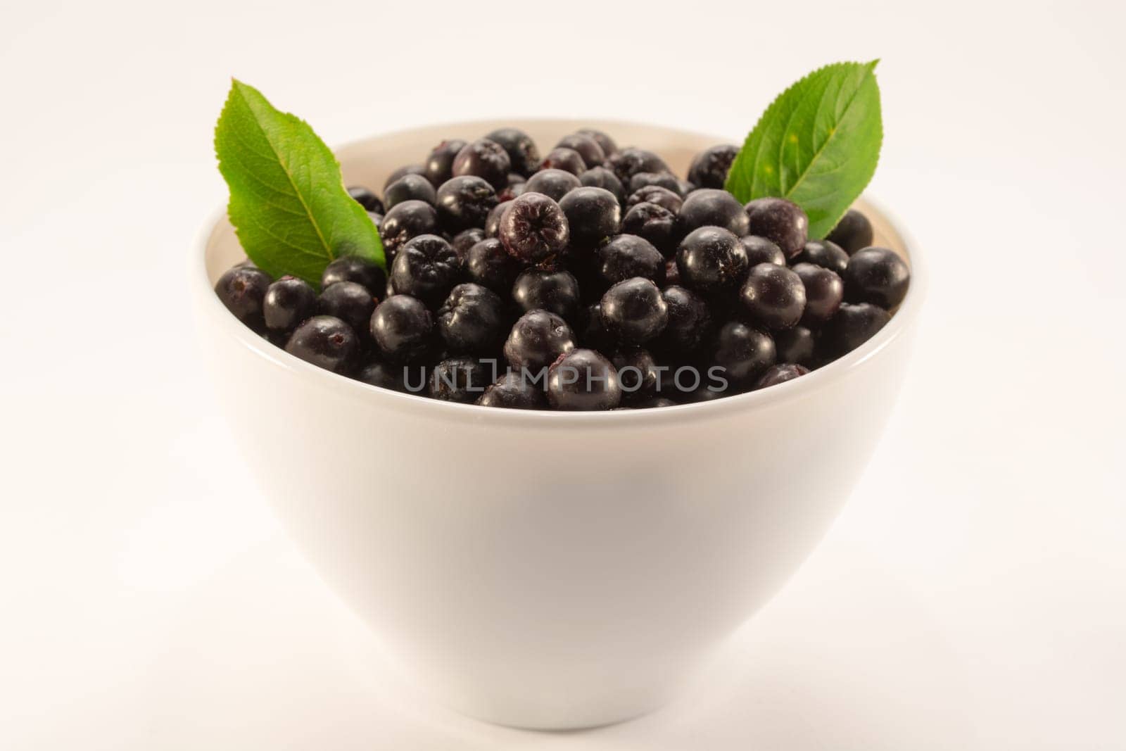 White bowl full with fresh and tasty aronia