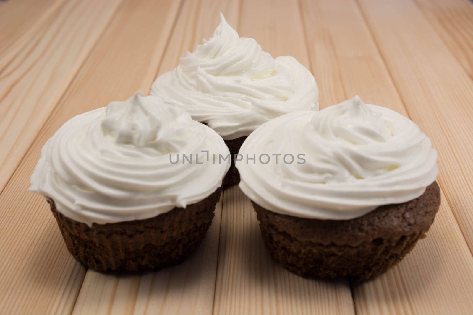 Muffins with cream on top of it sitting on bright wooden table
