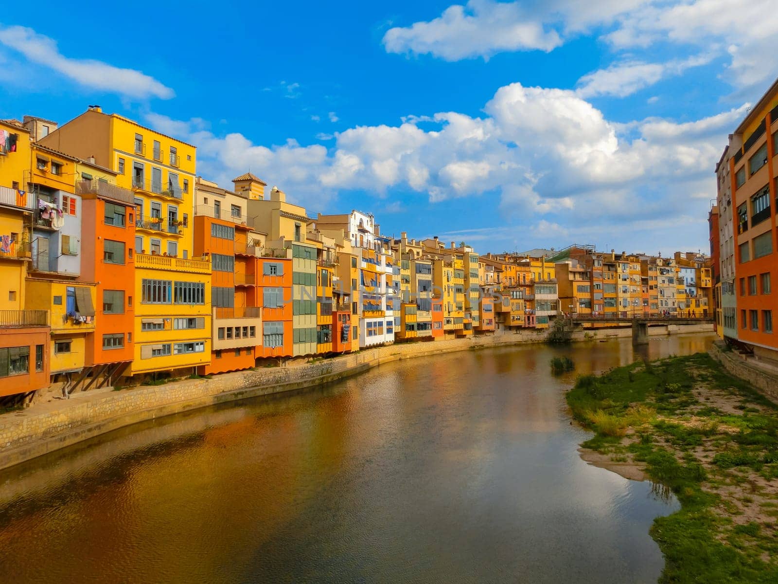 Colorful yellow and orange houses reflected in water river Onyar, in Girona, Catalonia, Spain.