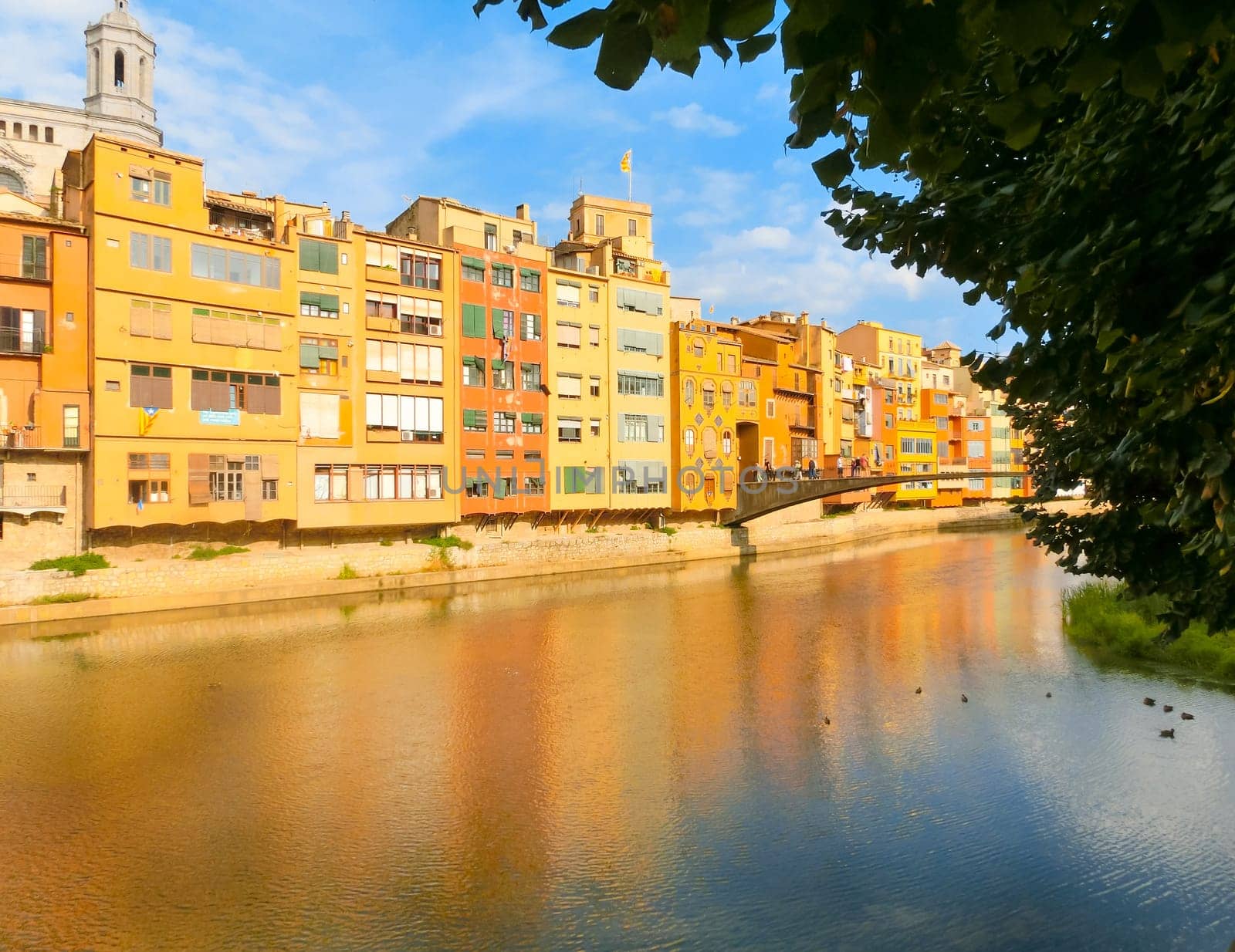 Colorful yellow and orange houses reflected in water river Onyar, in Girona, Catalonia, Spain.