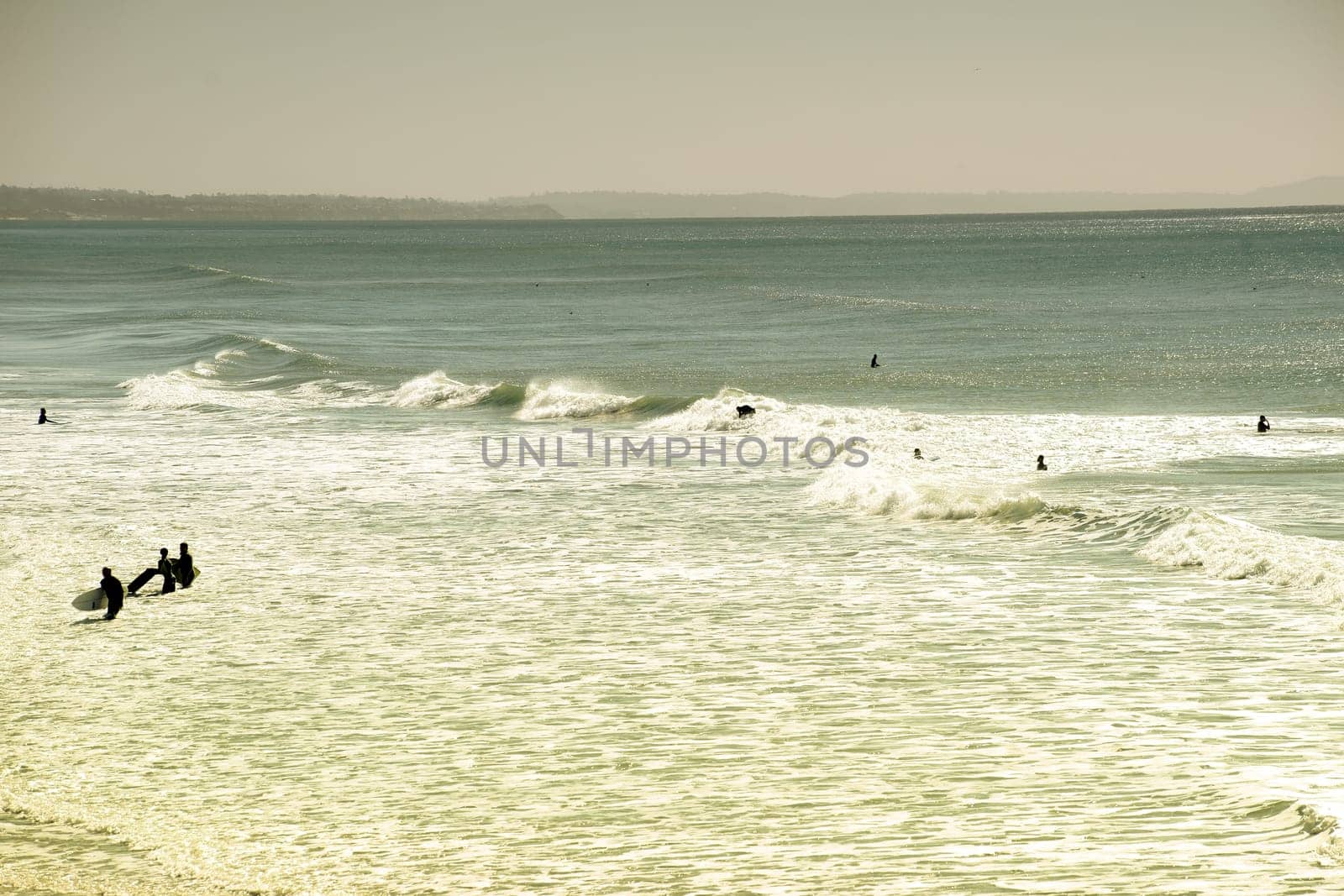 The silhouettes of surfers on the water in the backlight.