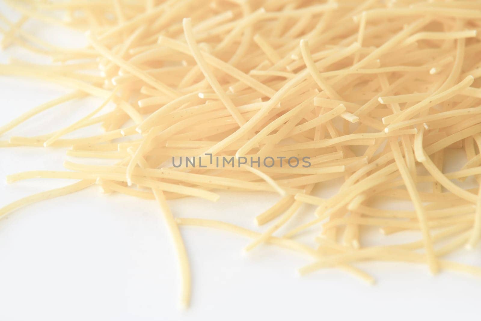 small dry pasta noodles on white background