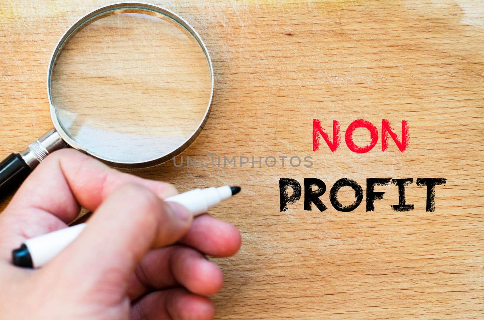 Human hand over wooden background and non profit text concept