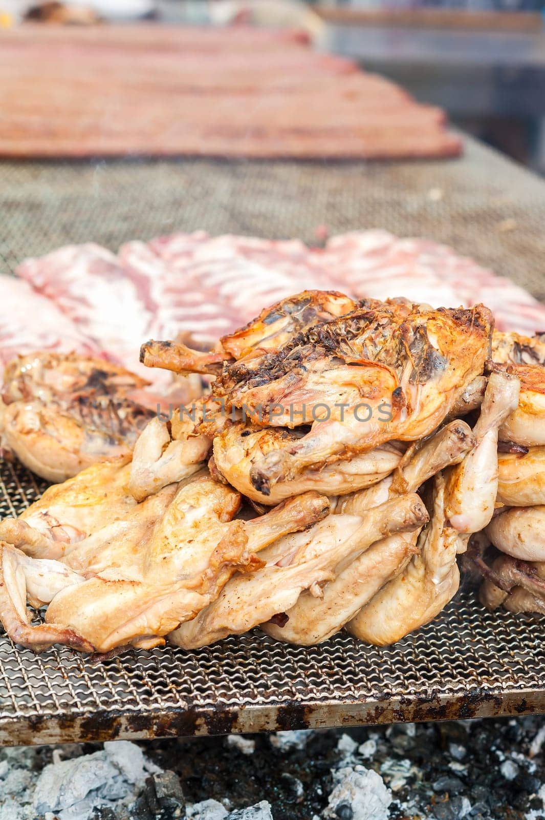 Inglese  Italiano.Chicken thighs cooked on the grill. During a village feast.