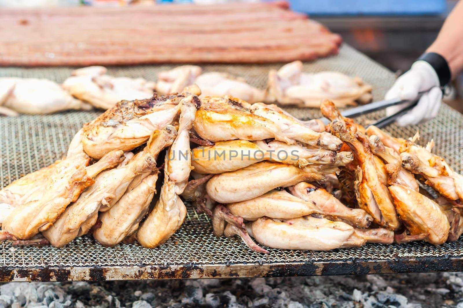 Inglese  Italiano.Chicken thighs cooked on the grill. During a village feast.