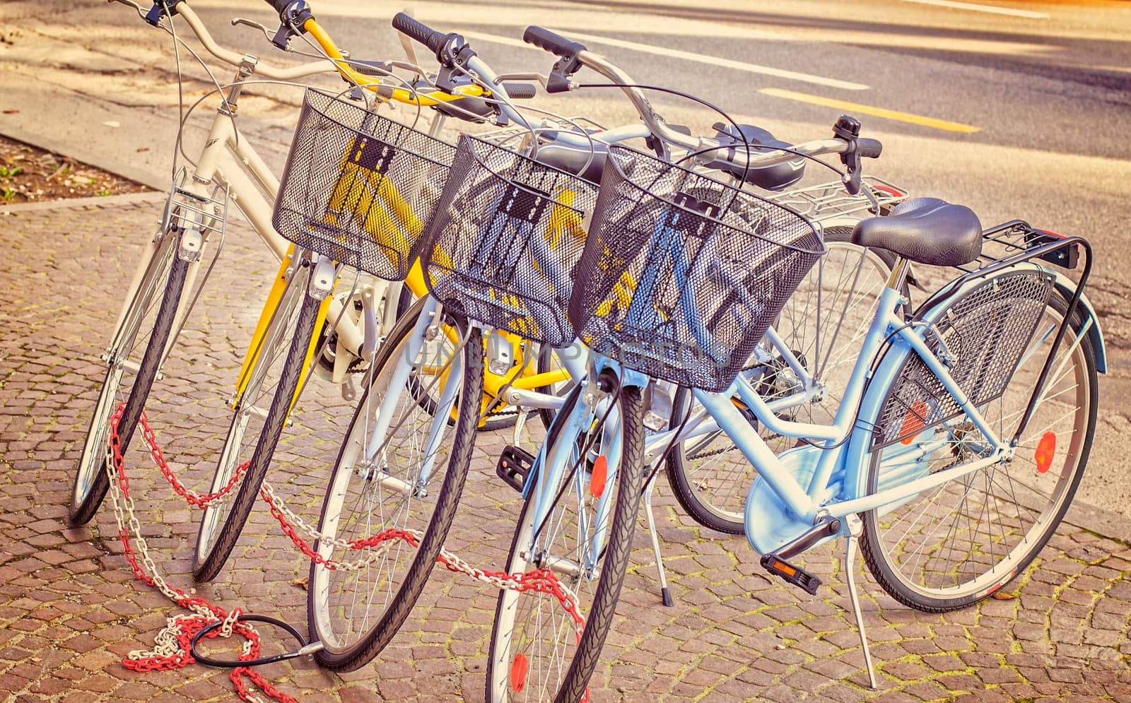 Four parked bicycles on the sidewalk, chained together. Vintage style