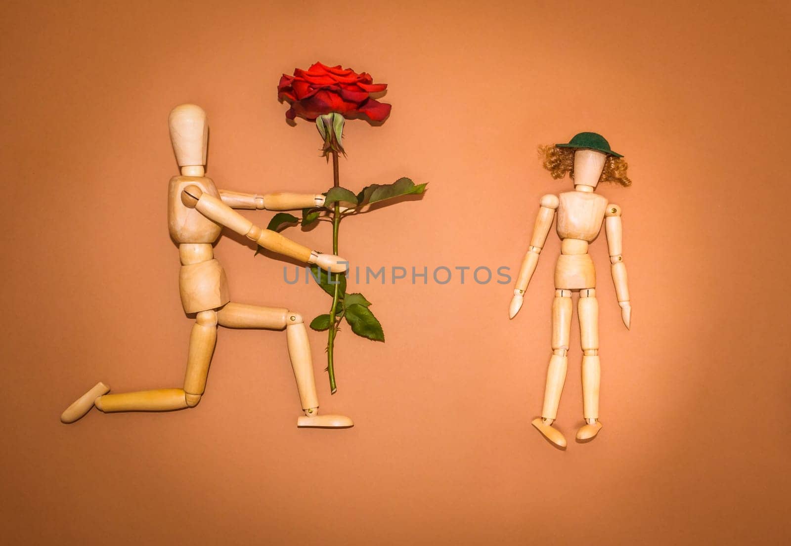 Red rose and figure wooden man and woman on brown background
