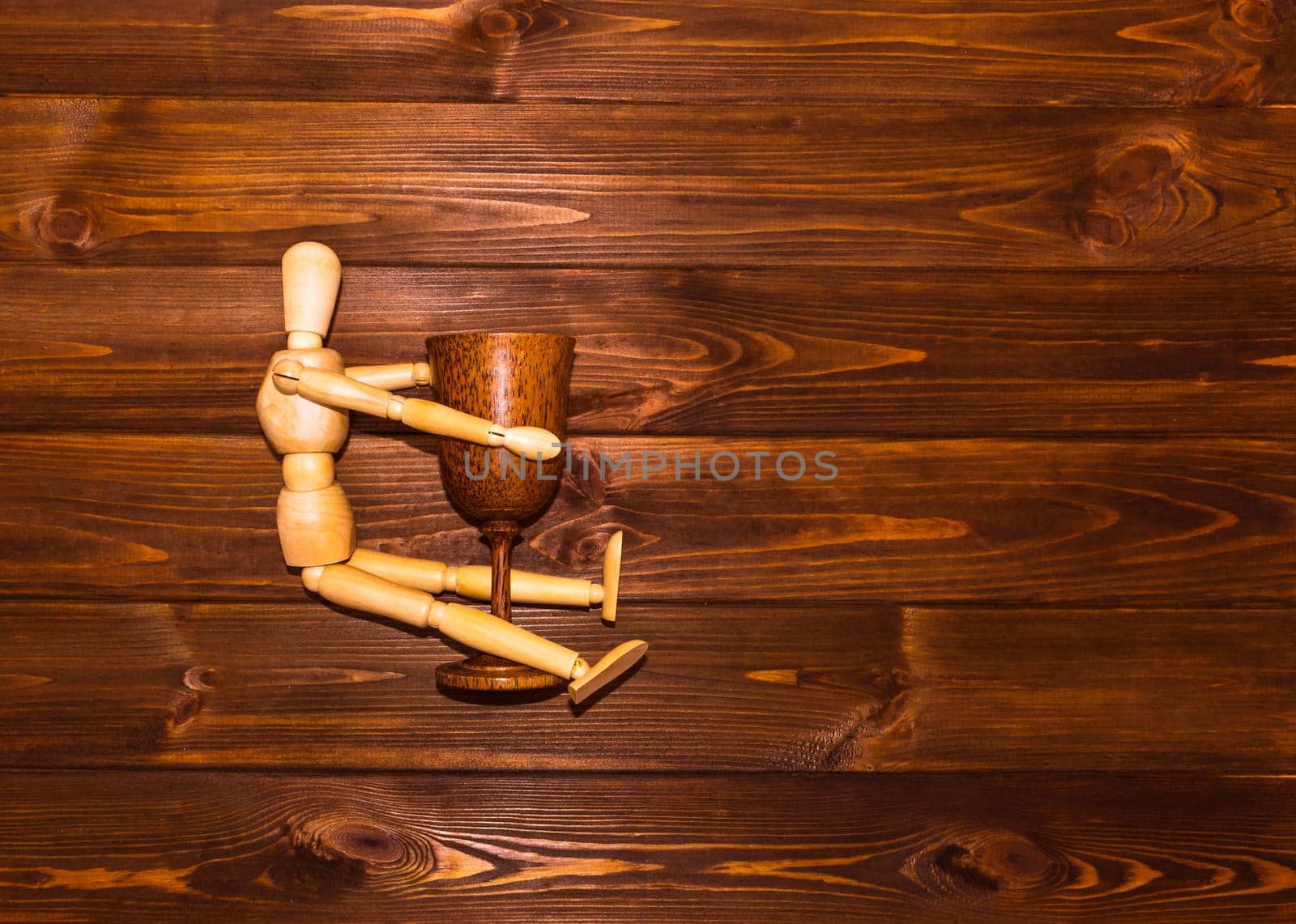 Wooden man with glass of wine on wooden background