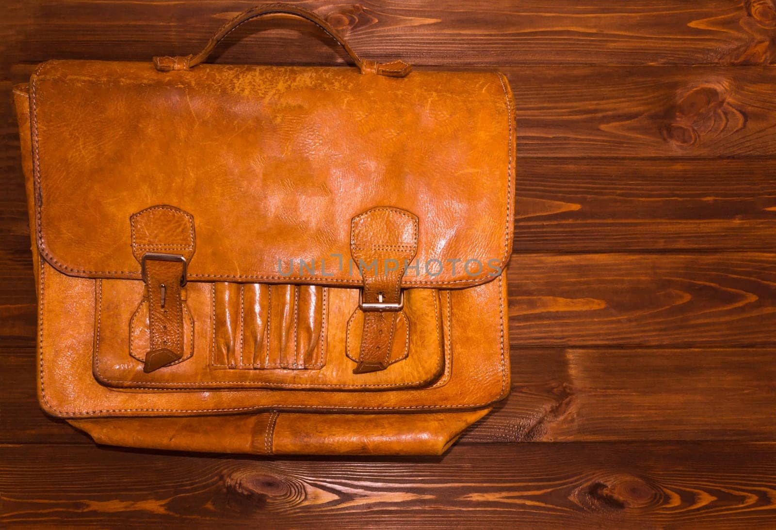 Old brown leather briefcase on wooden background