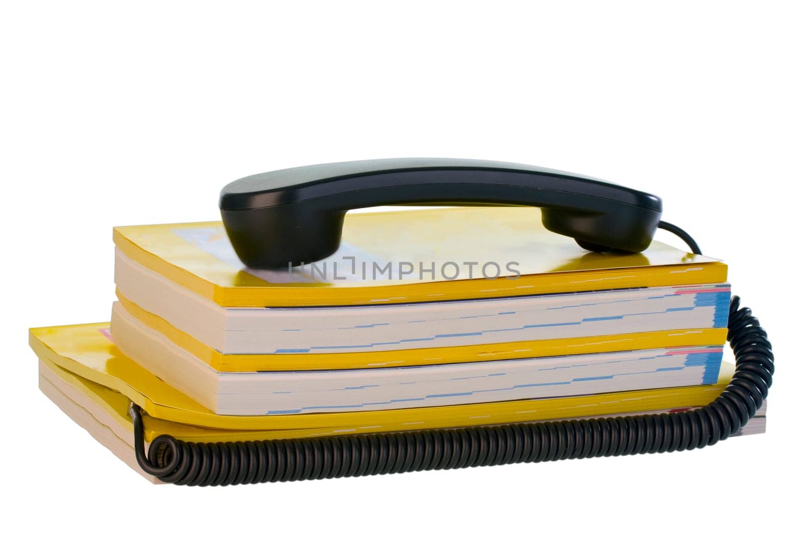 Telephone receiver lies on phone book cropped on white background