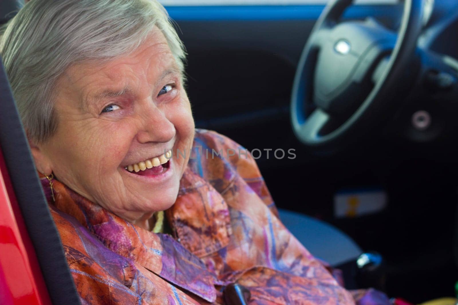 Laughing senior citizen as a passenger in the car