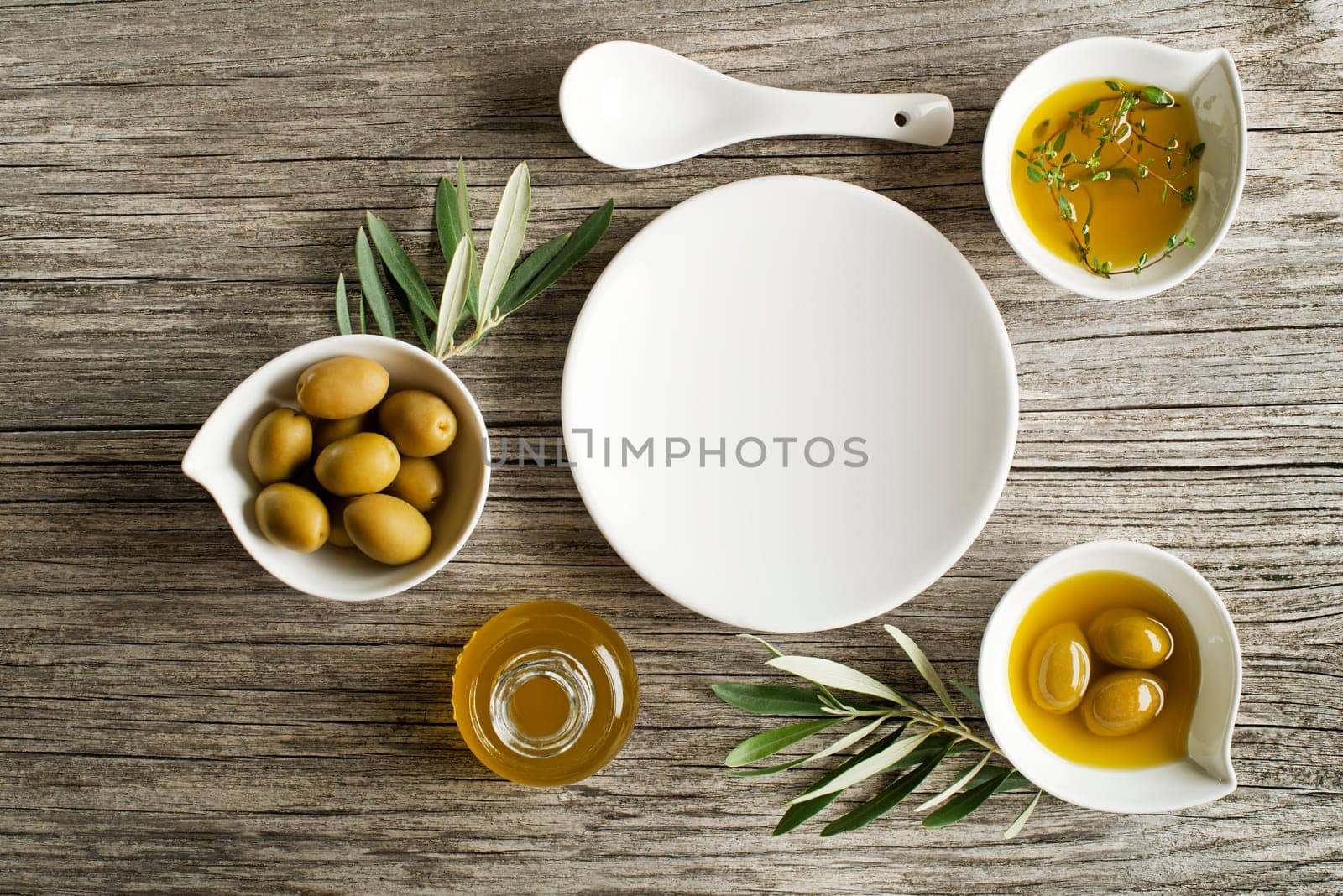 Olive oil with fresh herbs on wooden background