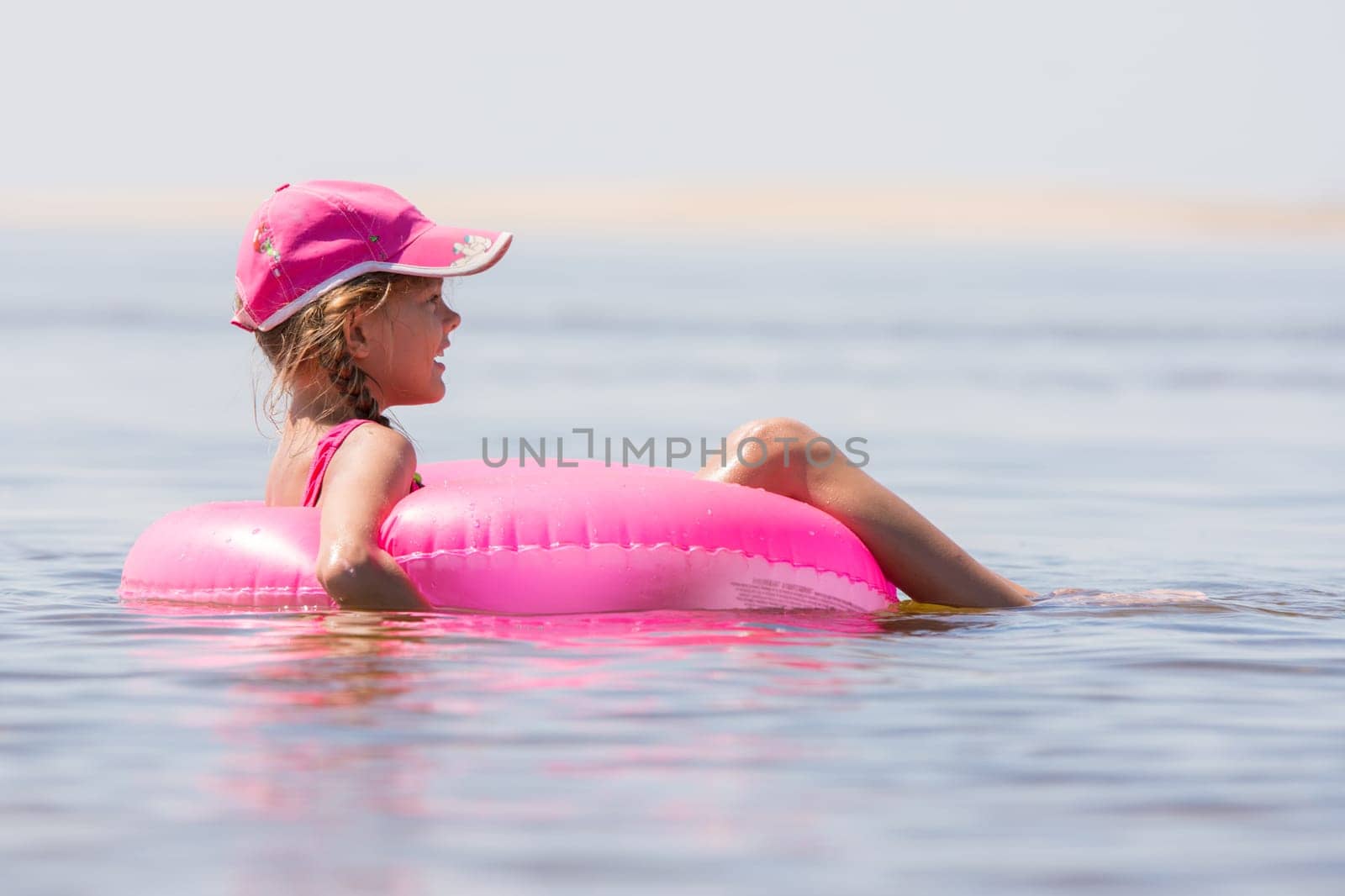 The girl in the cap swim in the river sat on the swimming circle