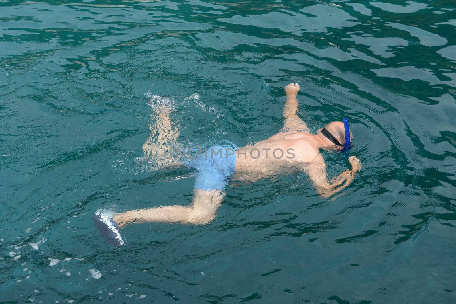 Man snorkelling in clear water to watch marine life.