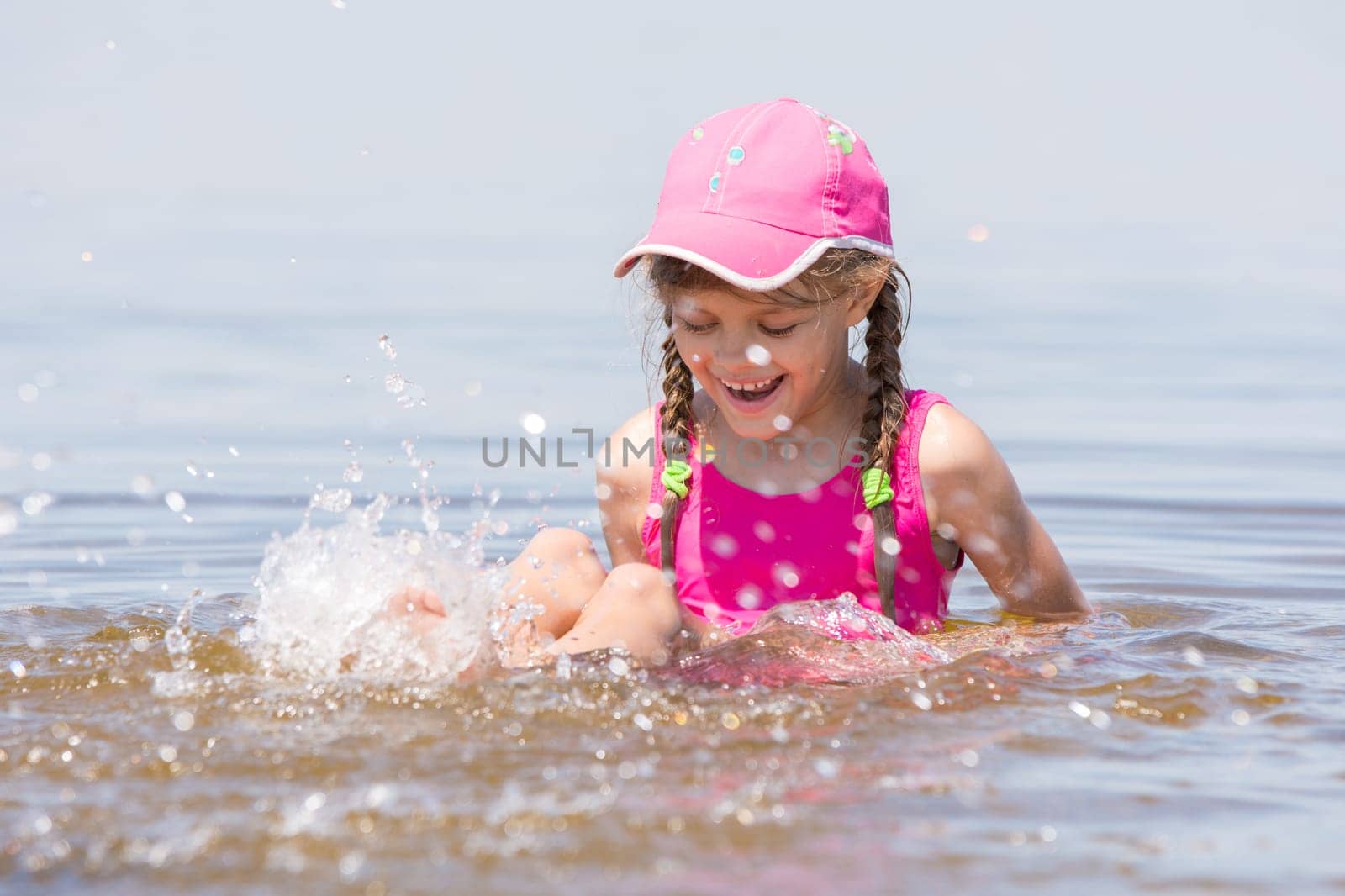 Girl splashing in cap sitting on a shelf in water