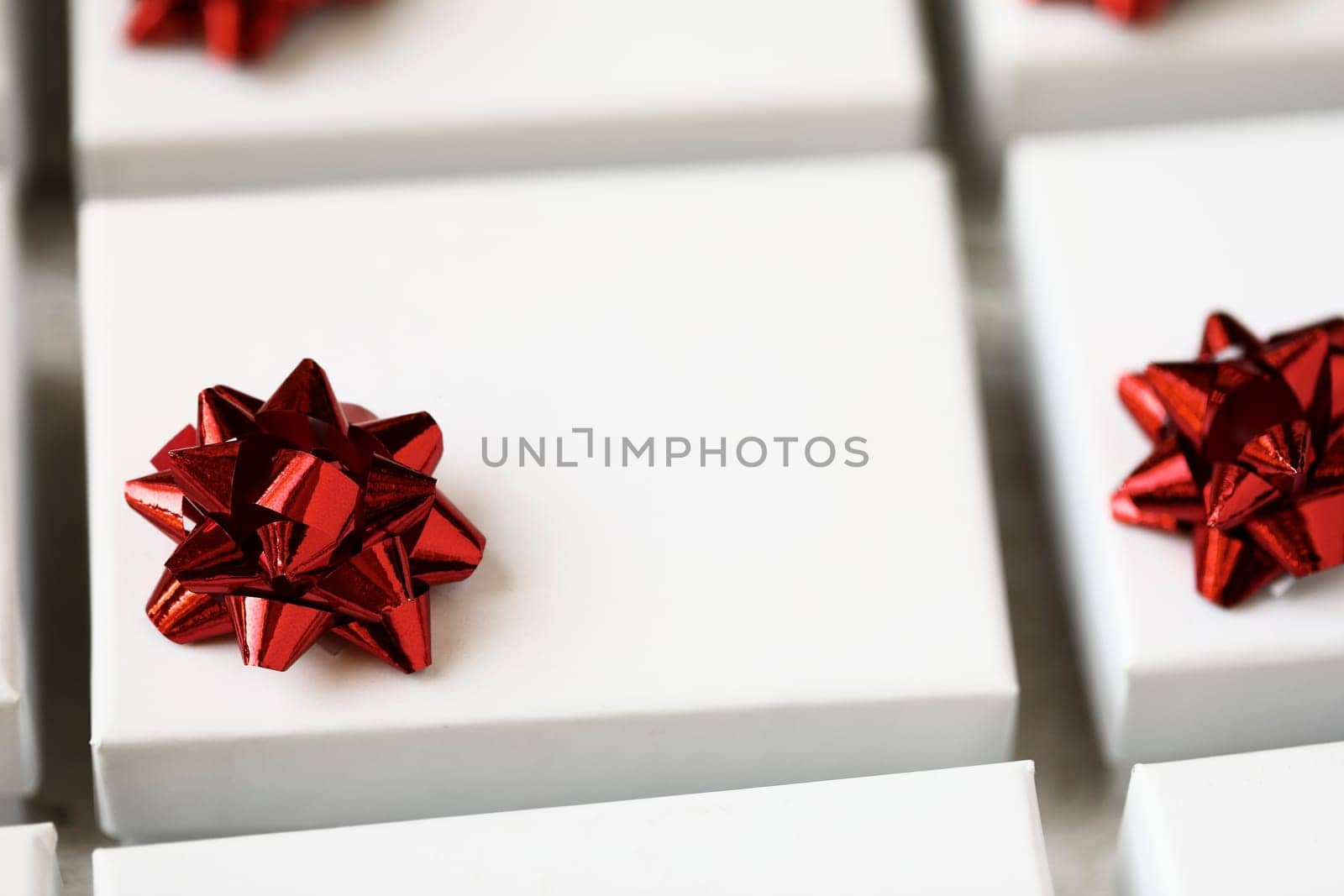 Close up of small white gift boxes with red bows.