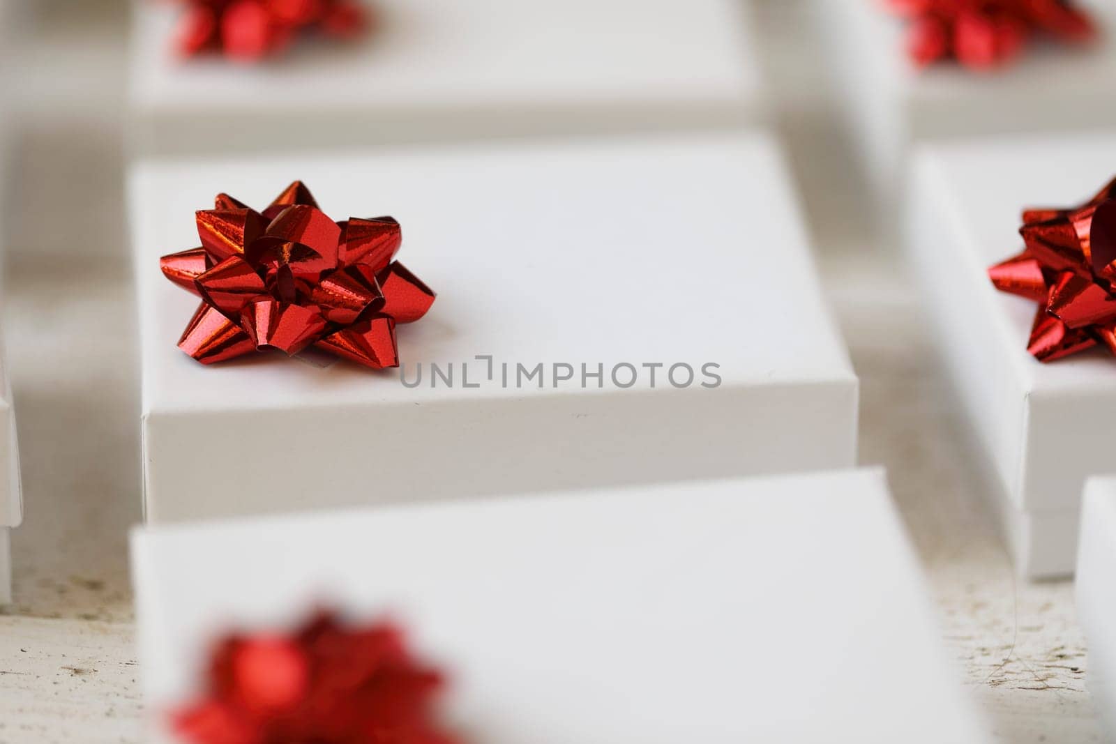 Close up of small white gift boxes with red bows.