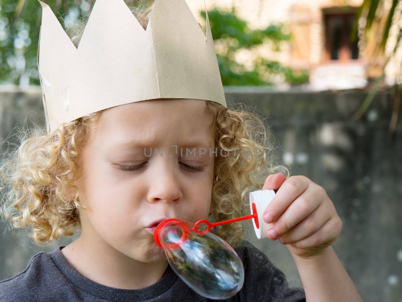 a little blond boy makes bubbles in the garden