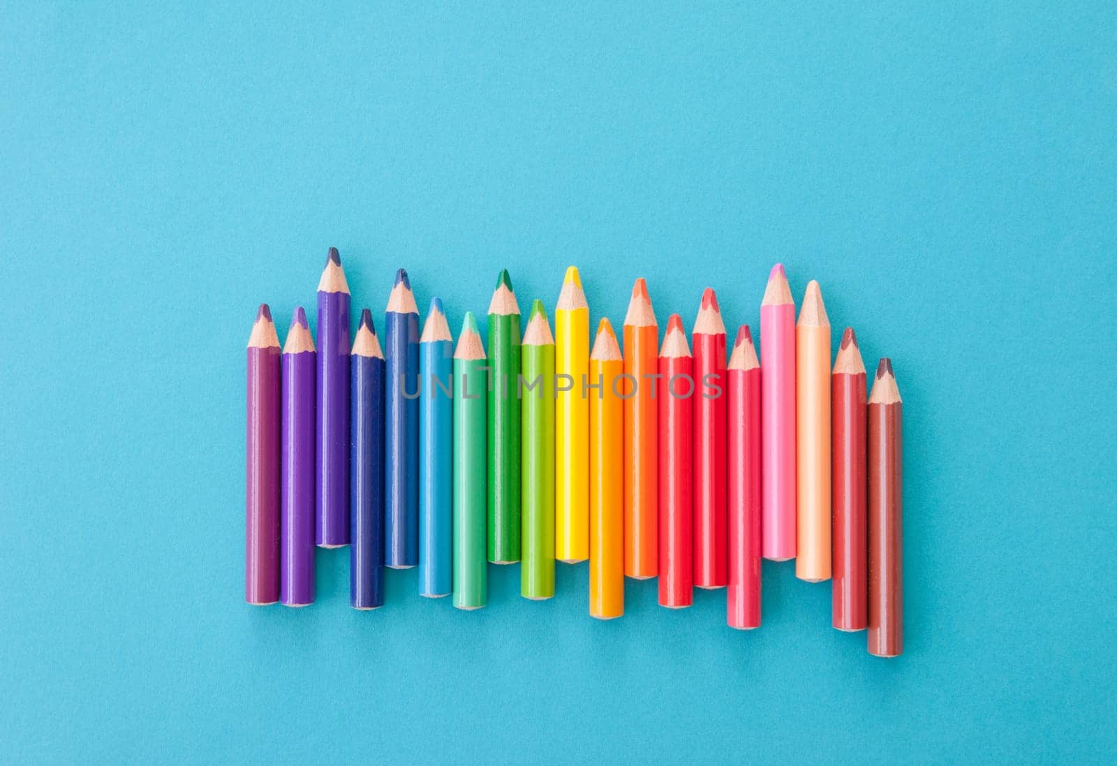 Colorful pencils in the gradient lined up on a blue background