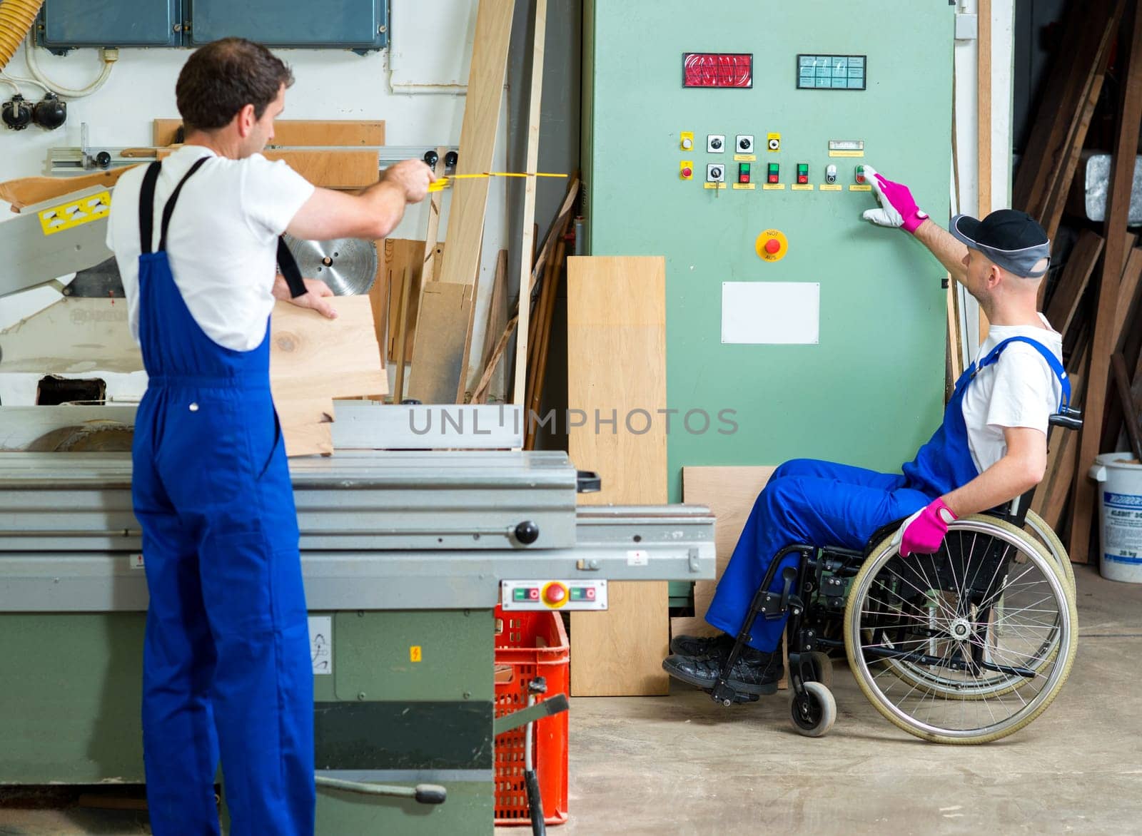 disabled worker in wheelchair in a carpenter's workshop with his colleague
