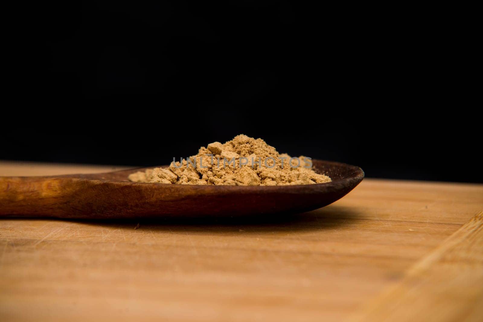 close up on powder ginger on wood with black background