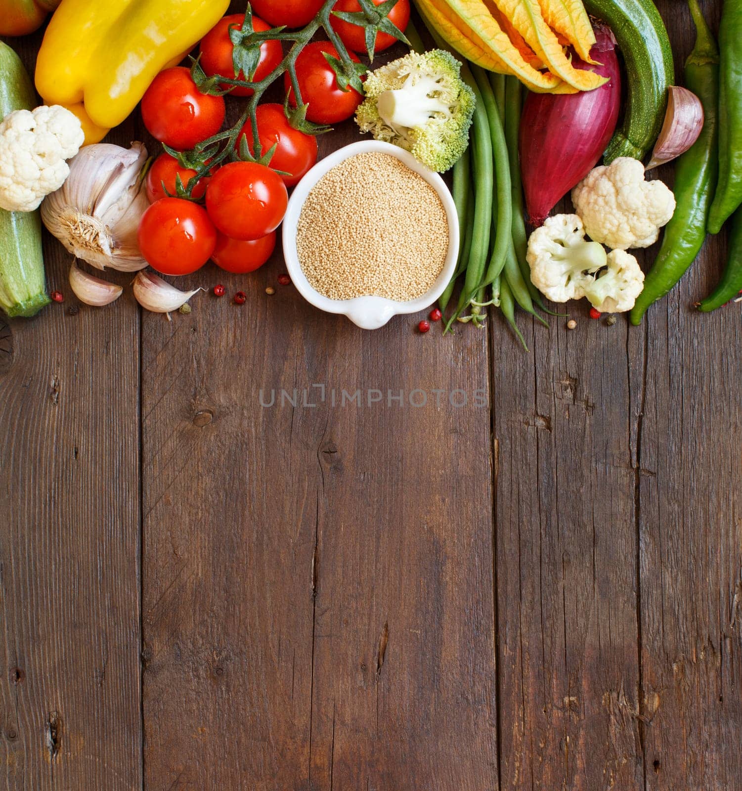 Raw Amaranth Grain in a bowl and vegetables on wood