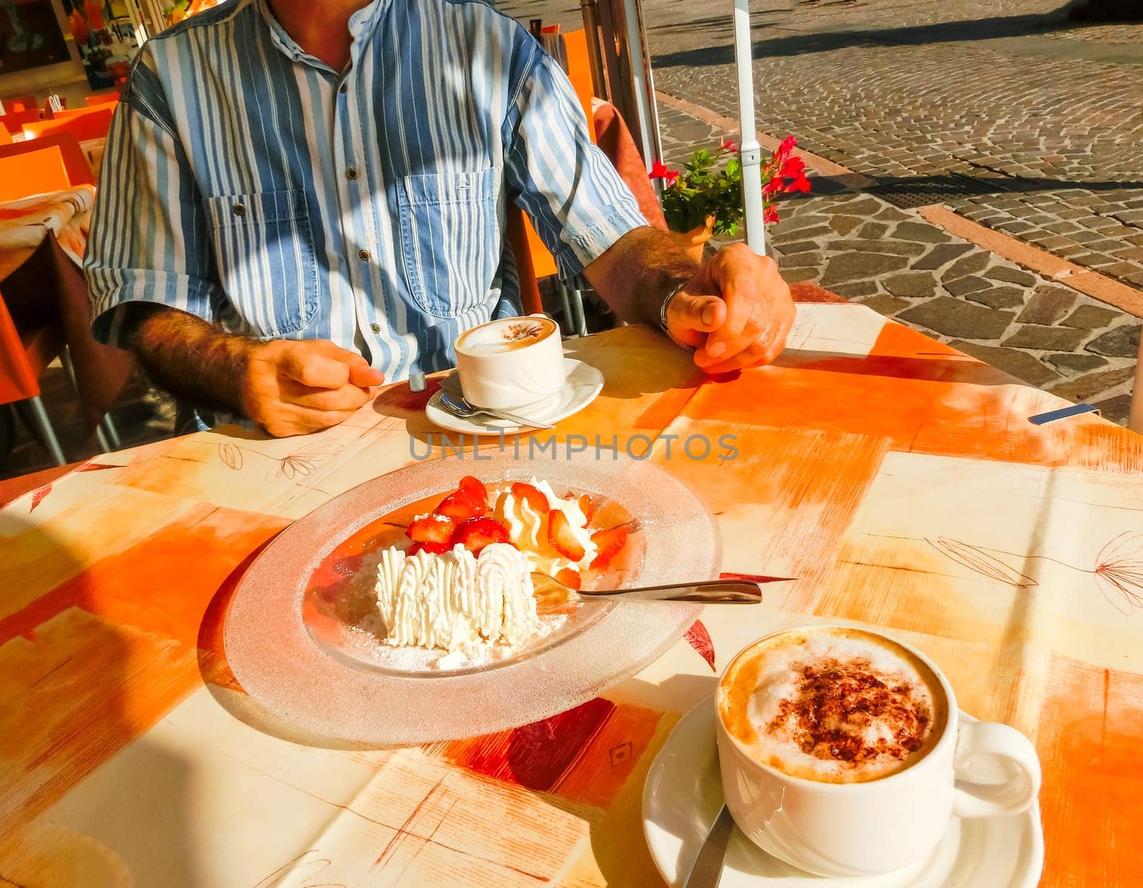 The dessert strawberries with cream and cup of coffe on the table of the outdoor cafe on the italian sidewalk. Taken during Italian vacation.