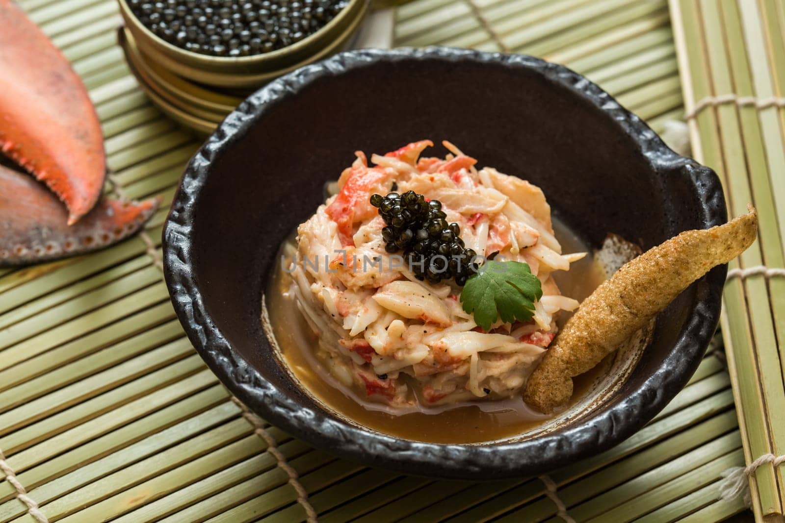 Crab meat in a dish on wood table with black caviar