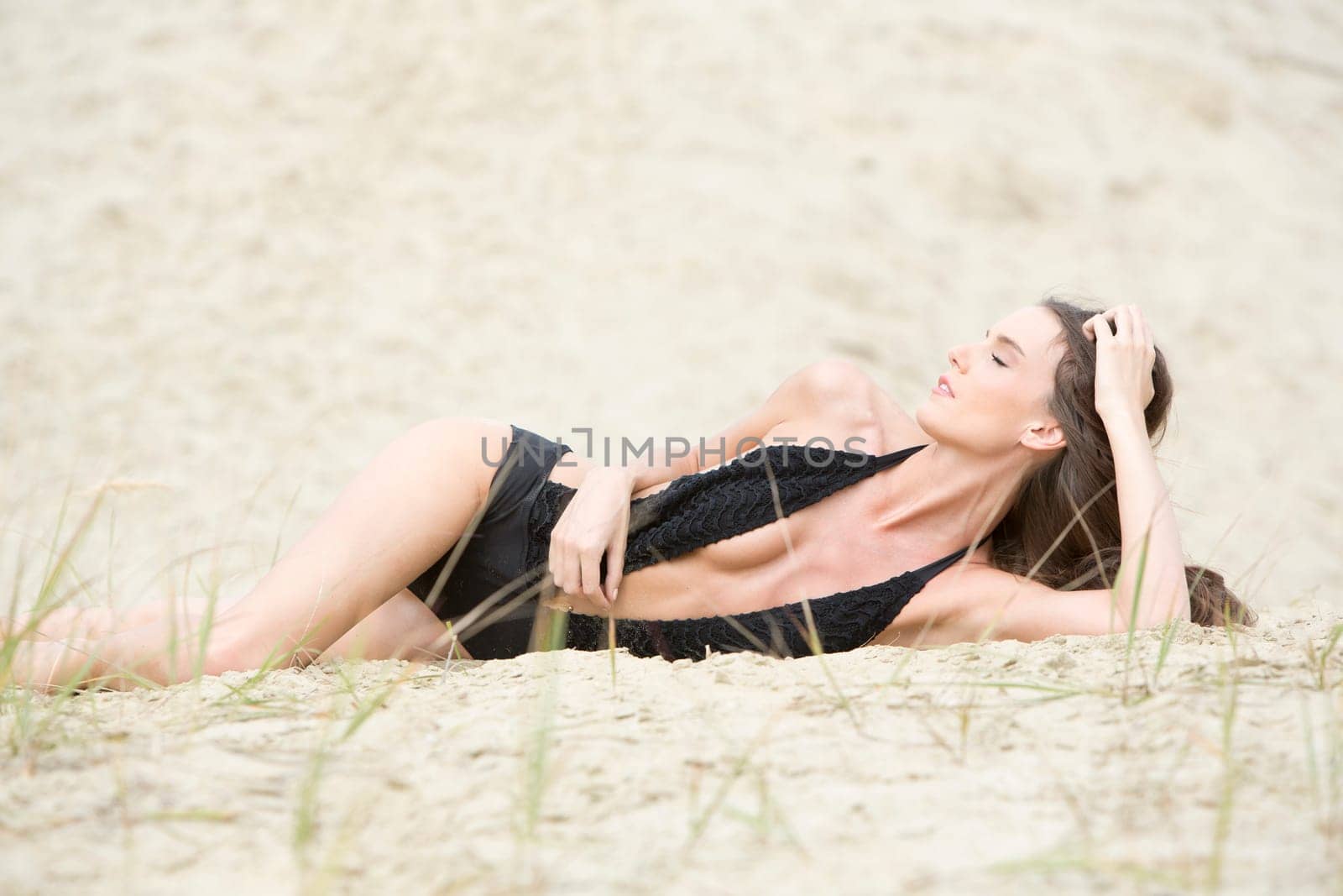 Woman with black swimsuit in the sand