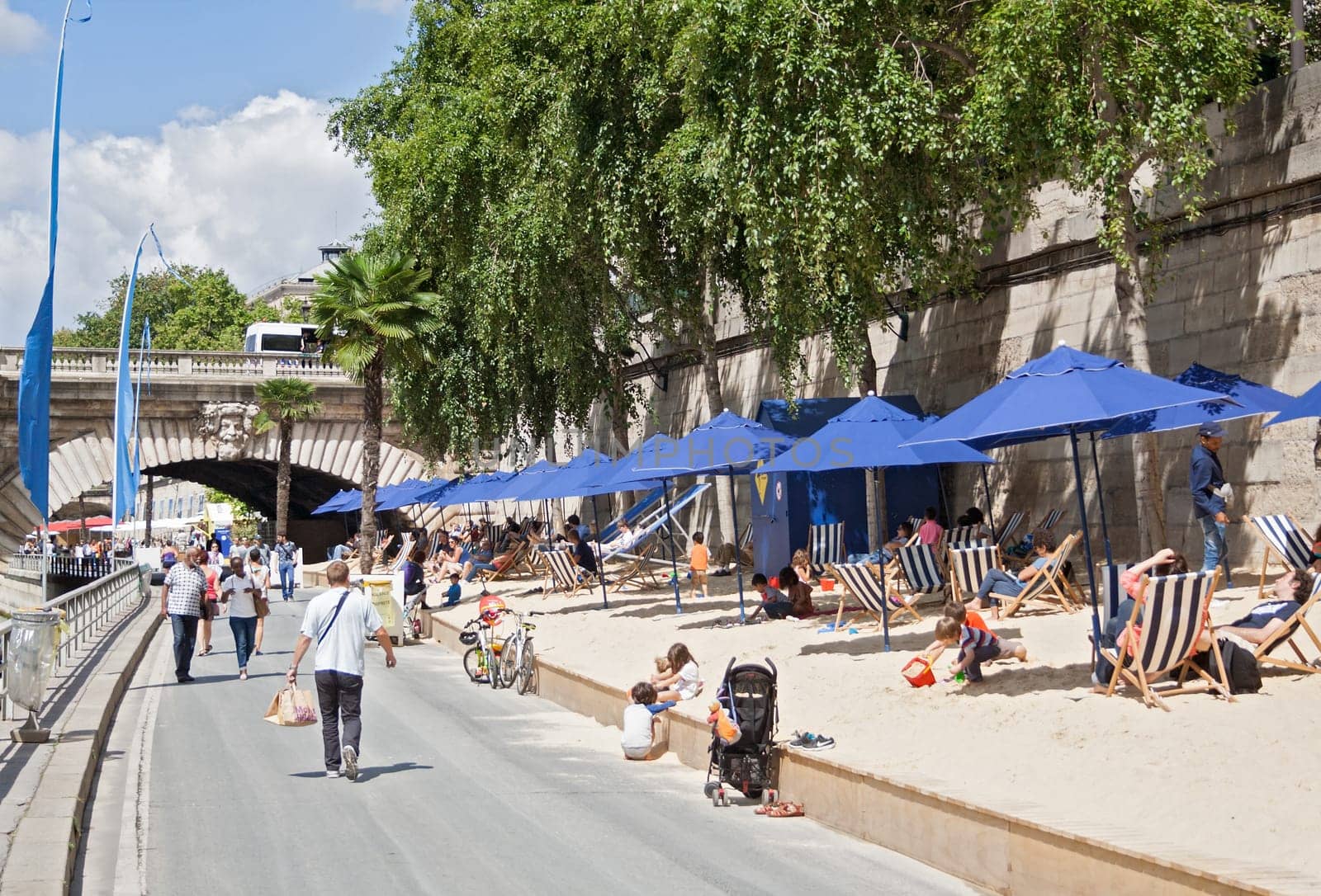 people lying in the sun on the banks of the seine in paris