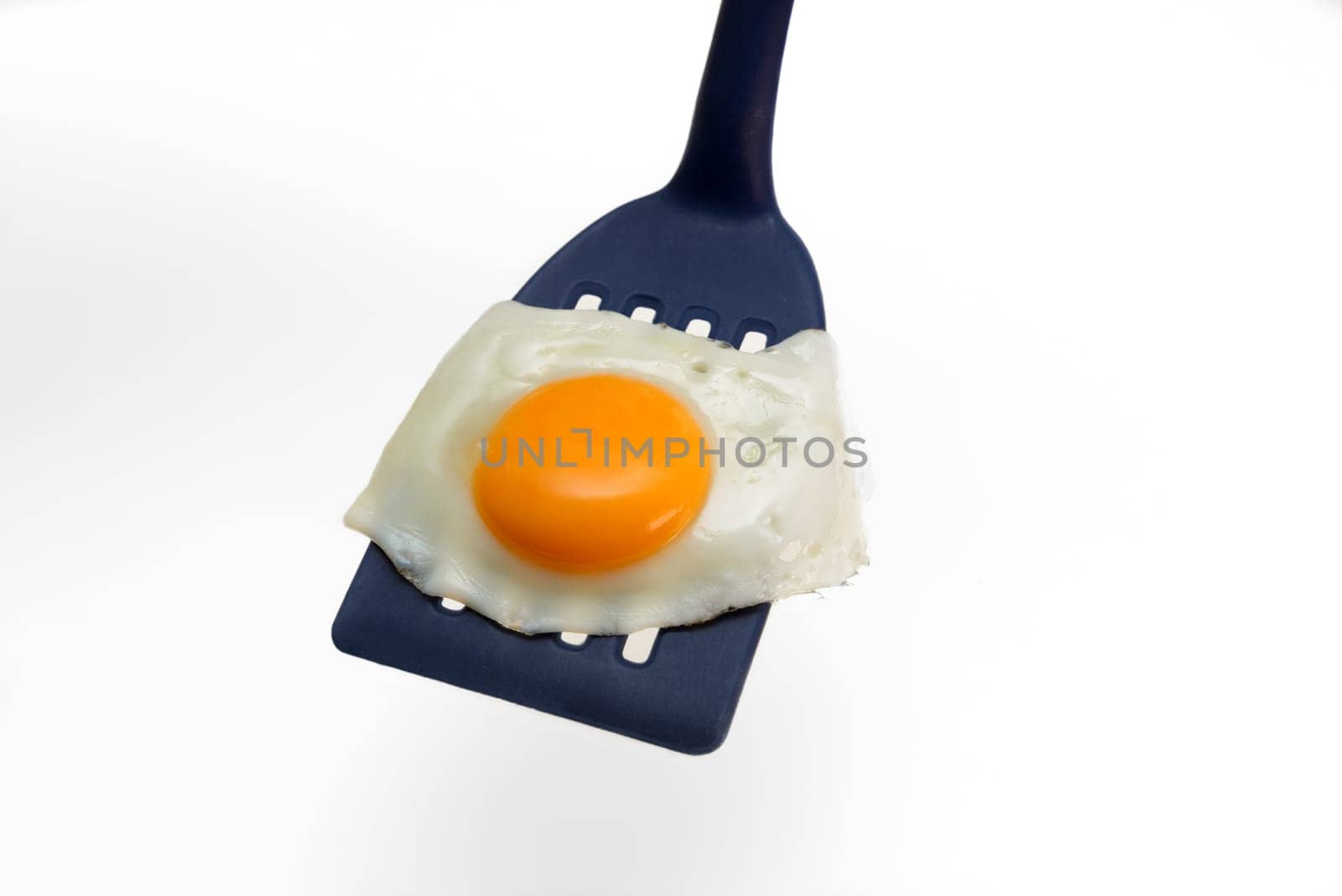 Fried egg on the spatula, ready to be served. White background.