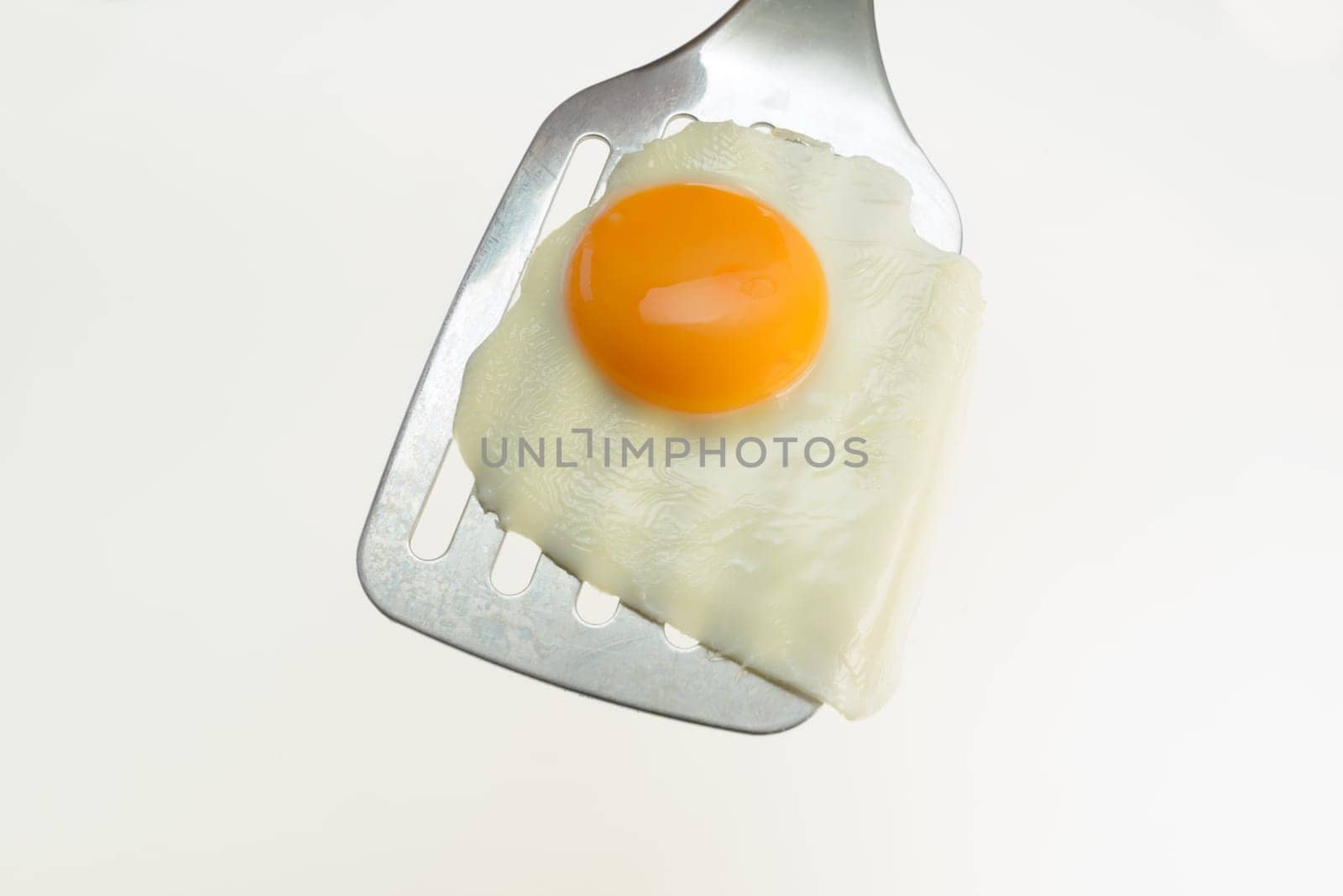 Fried egg on the spatula, ready to be served. White background.