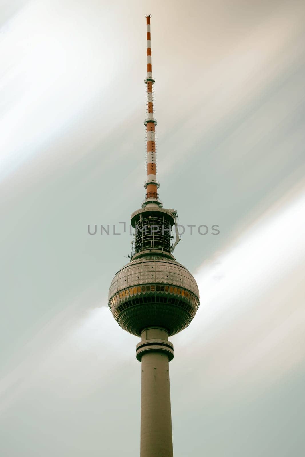 The lower view of the Berlin TV Tower with blurred clouds in the background.