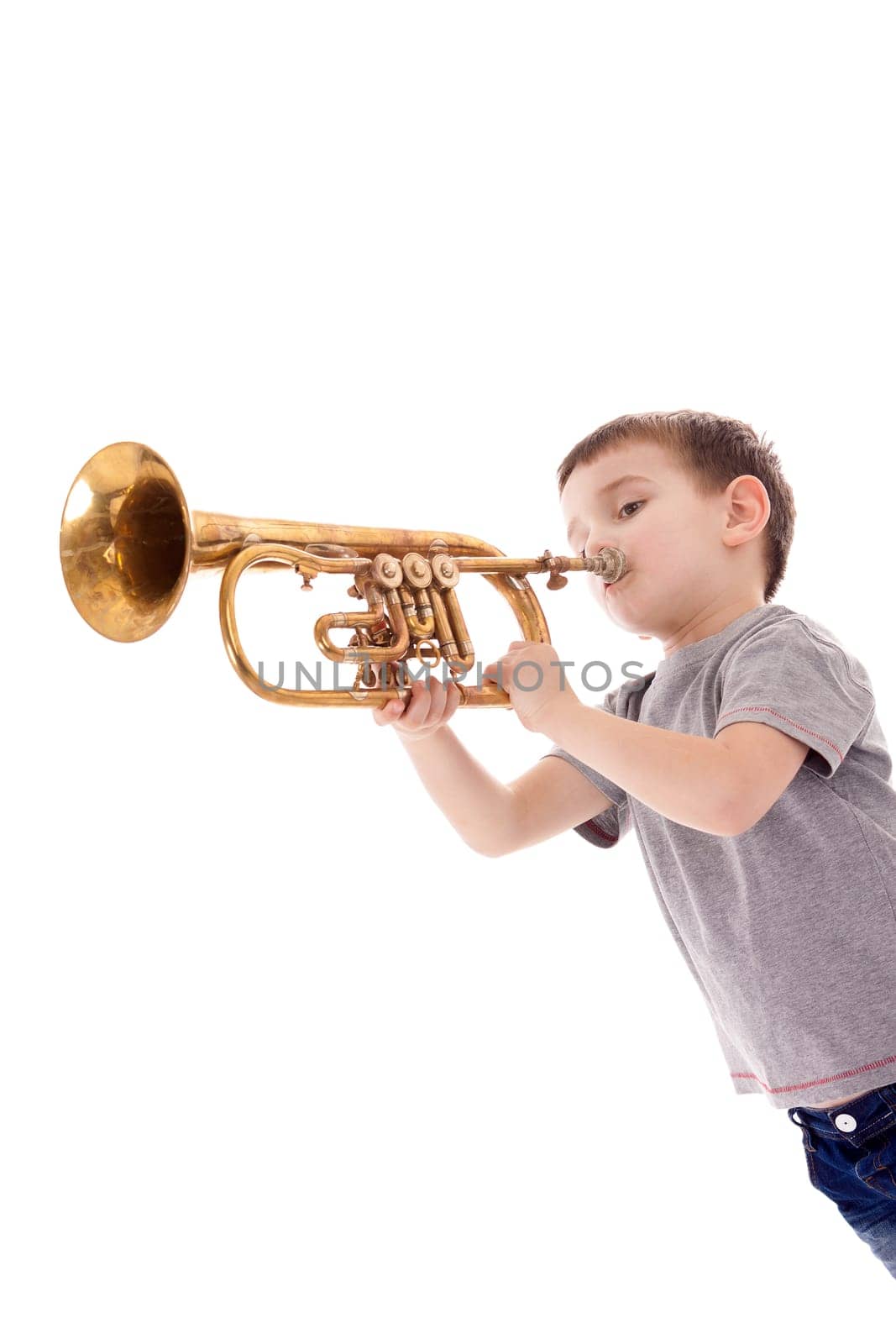 young boy blowing into a trumpet against white background
