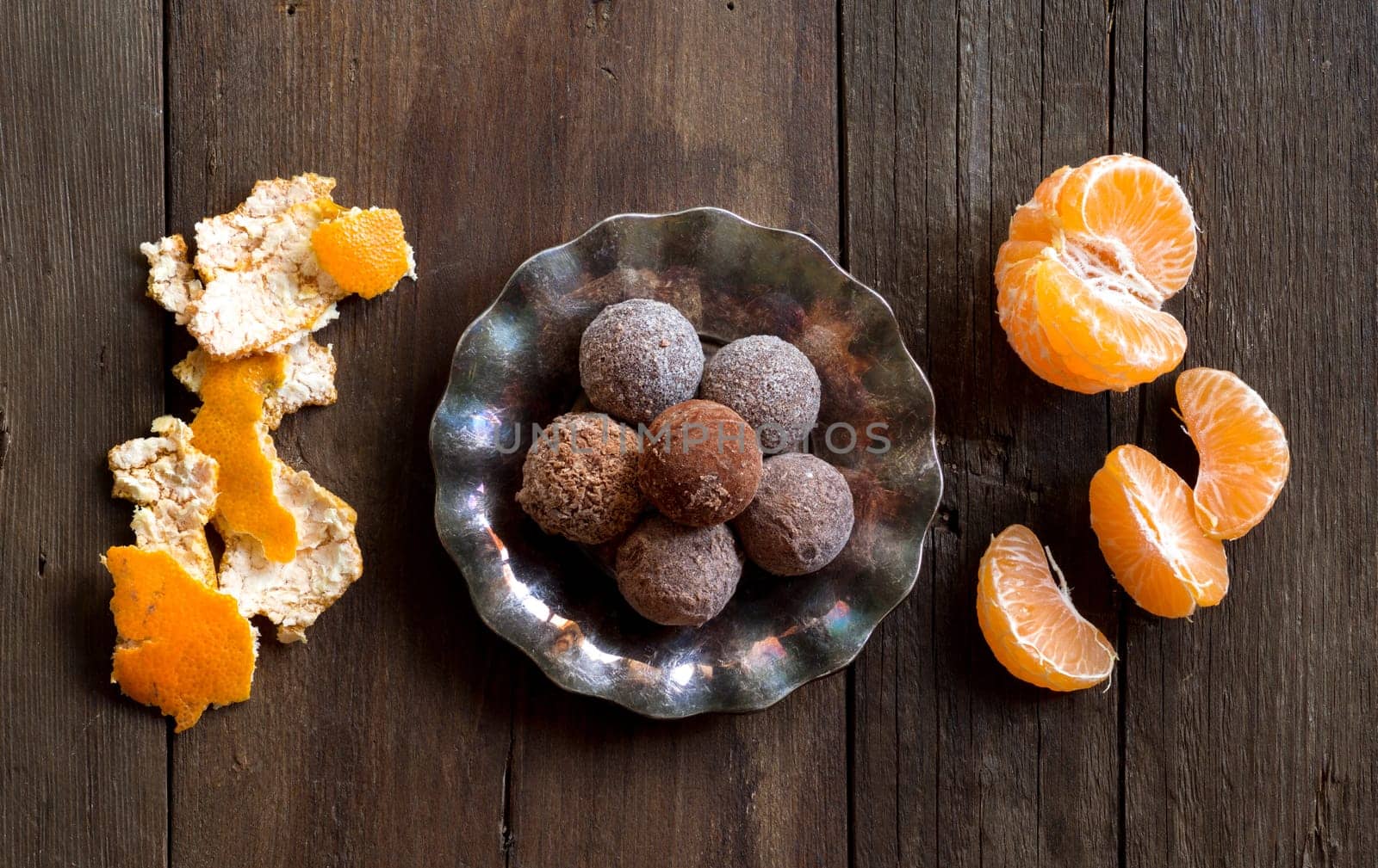 Chocolate truffles and tangerins on a wooden table