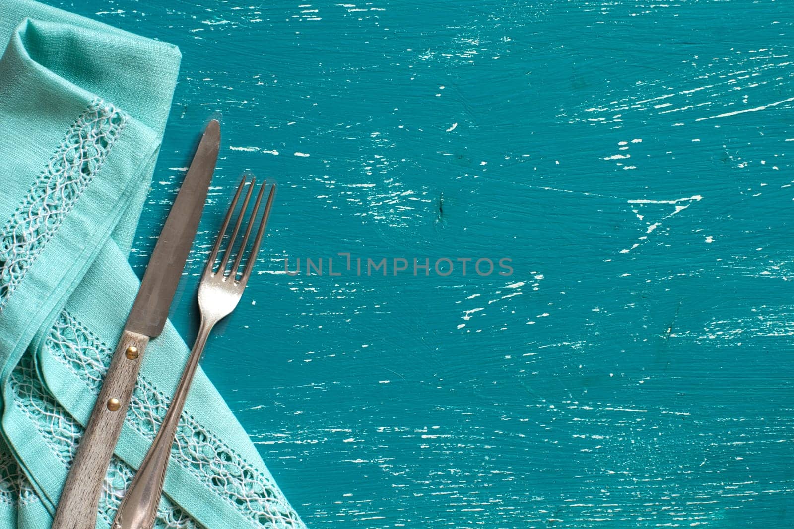 Vintage fork and knife on napkin on a turquoise wood