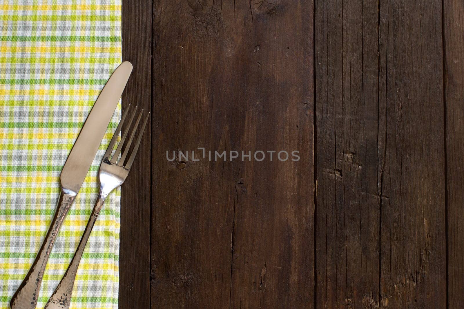Vintage fork and knife on a colorful napkin on wooden table