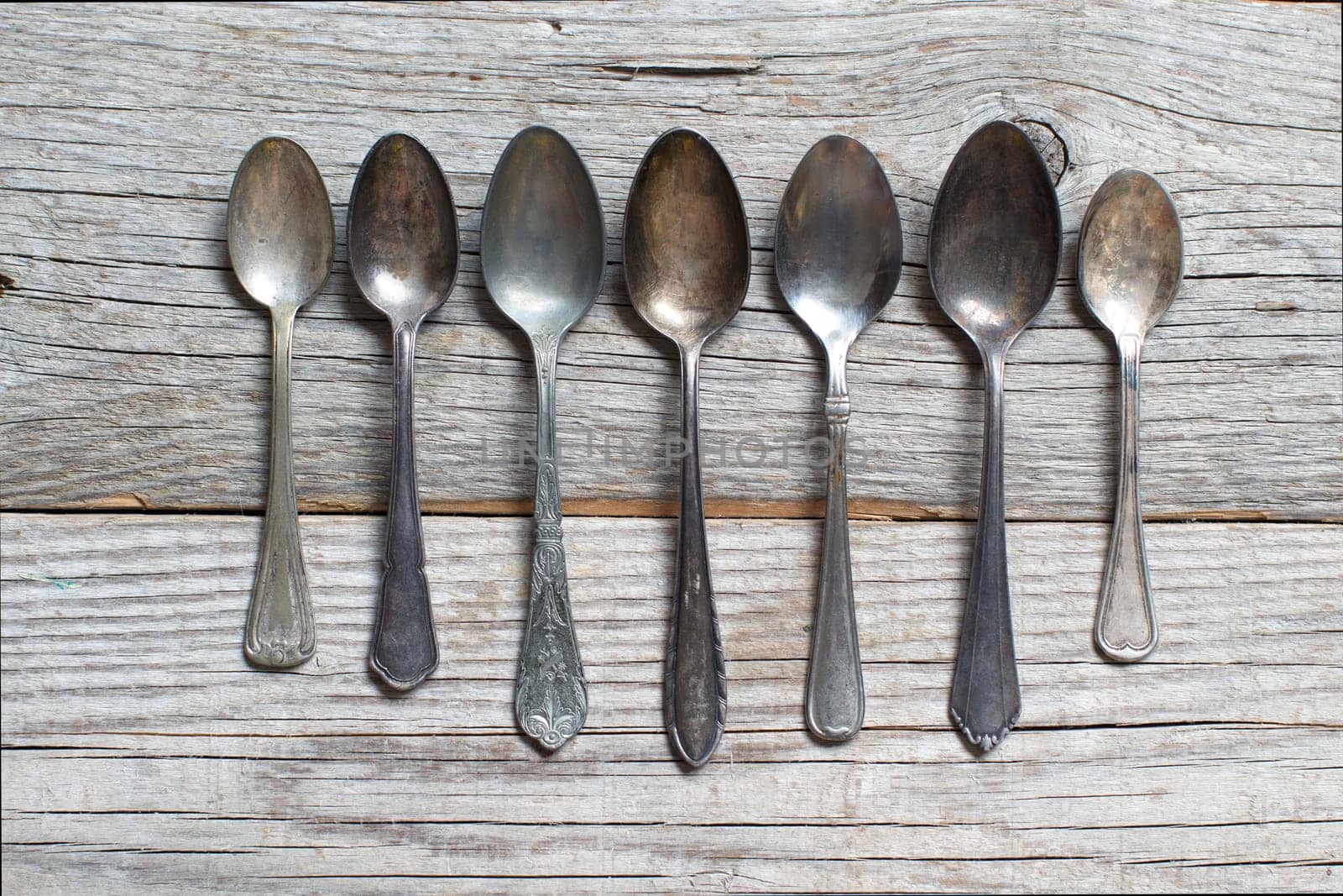 Vintage spoons with patina on old wooden table